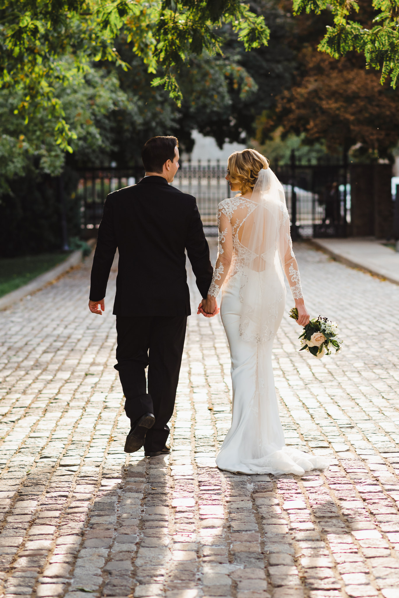 bride and groom stroll hand in hand along a brick pathway in an iconic downtown Toronto wedding