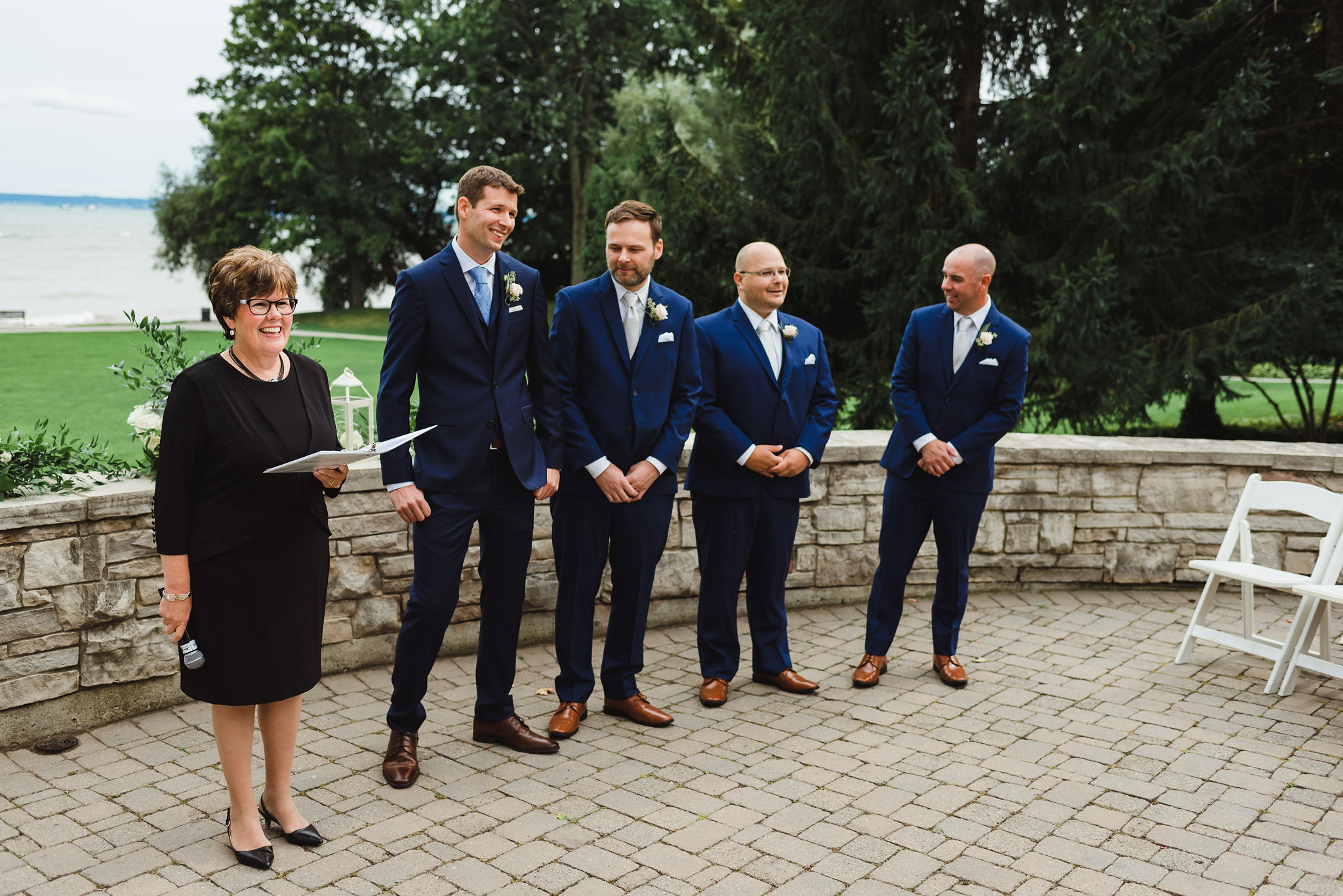 groom stands in front of Lake Ontario alongside his 3 groomsmen and the officiant on the other side as he awaits his bride to enter the ceremony at La Paletta Mansion in Burlington Ontario