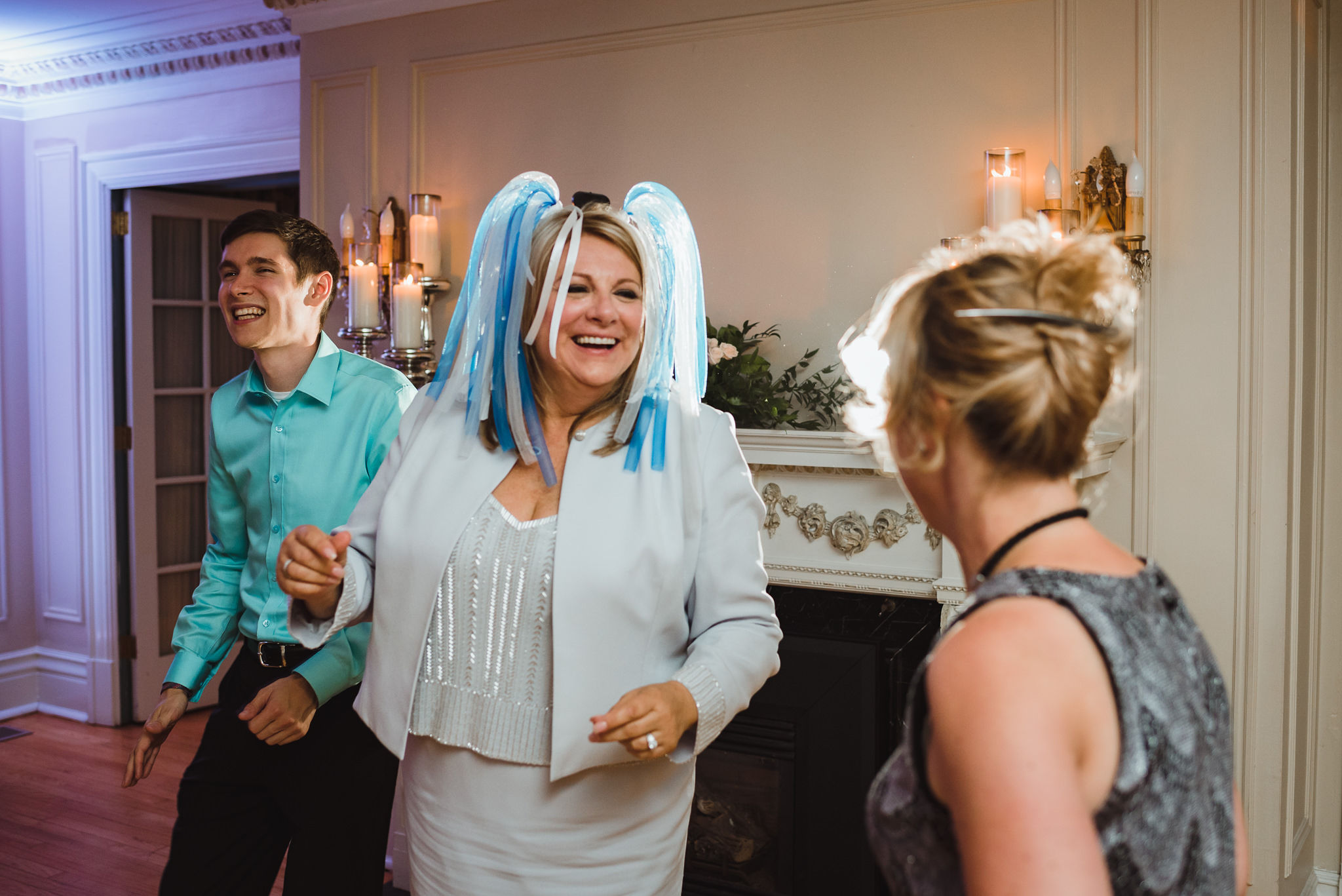 woman wearing a blue and white wig dancing with a couple other wedding guests during the reception at La Paletta Mansion in Burlington Ontario