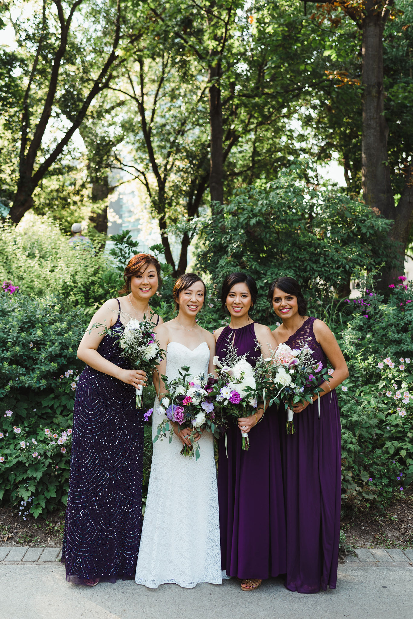 bride standing in the park with her 3 bridesmaids in purple dresses before her Parisian inspired wedding at La Maquette in Toronto Ontario