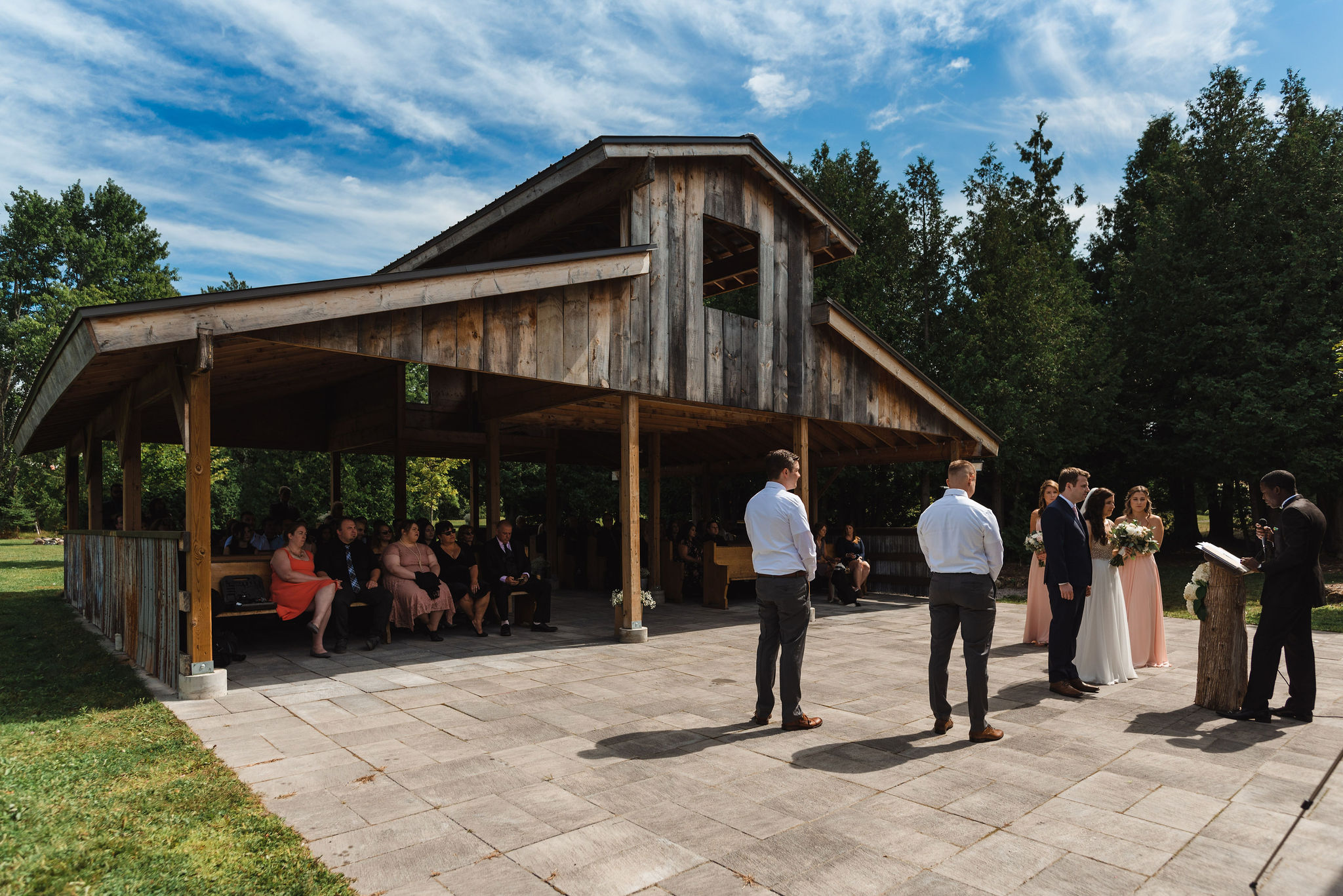 bride and groom getting married on stone patio in front of open style barn at Carvers cottage in Toronto
