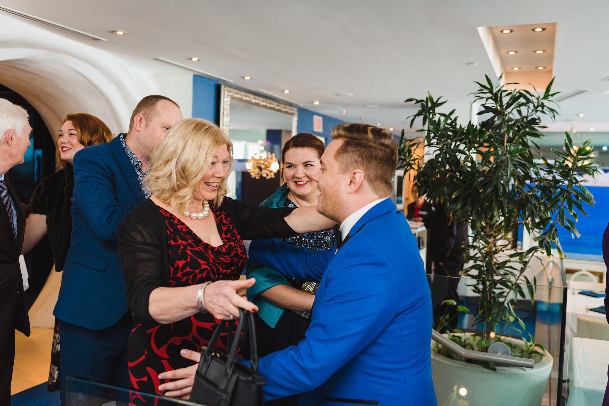 groom in bright blue suit hugging wedding guests as they arrive at the Hilton Niagara Falls