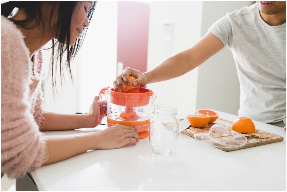 Couple squeezing an orange to make orange juice. 