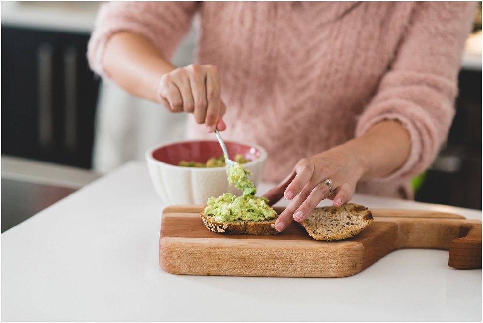 Woman smearing avocado on toast. 