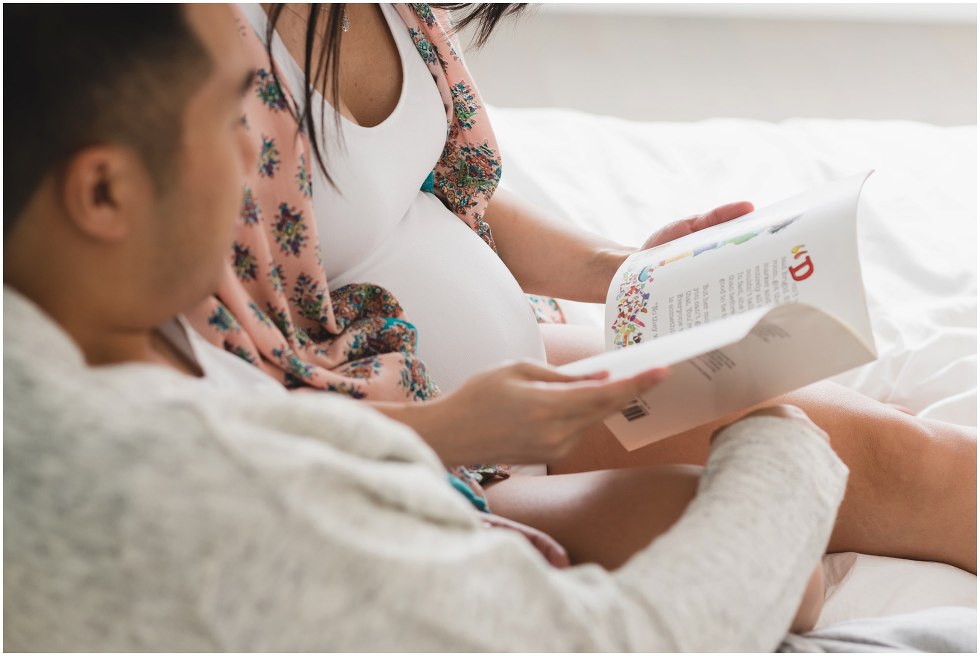 Parents to be looking at a baby book. 