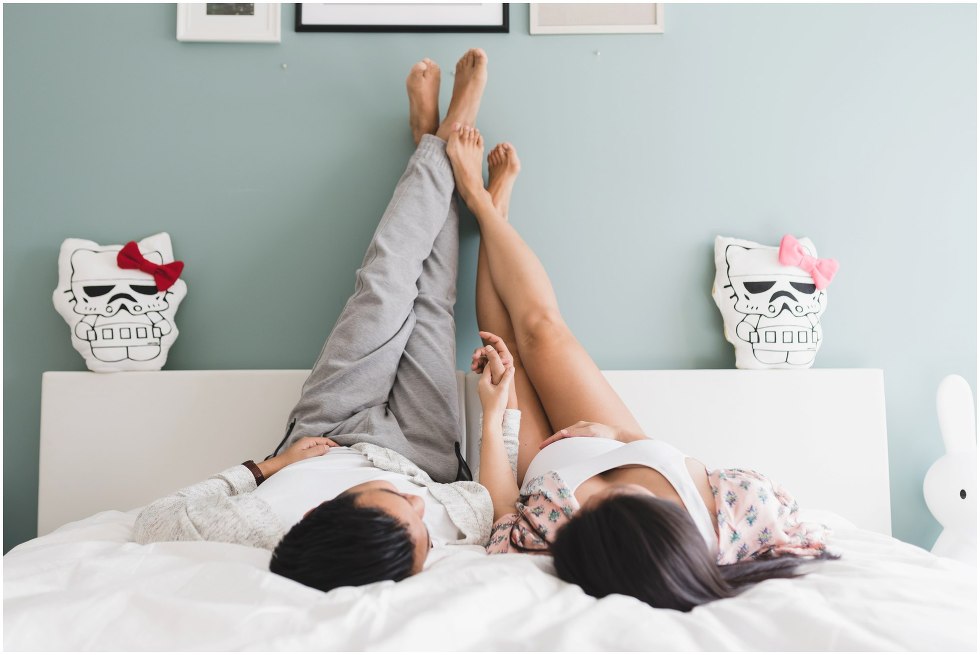 Couple rest their feet up on the wall in their bedroom. 
