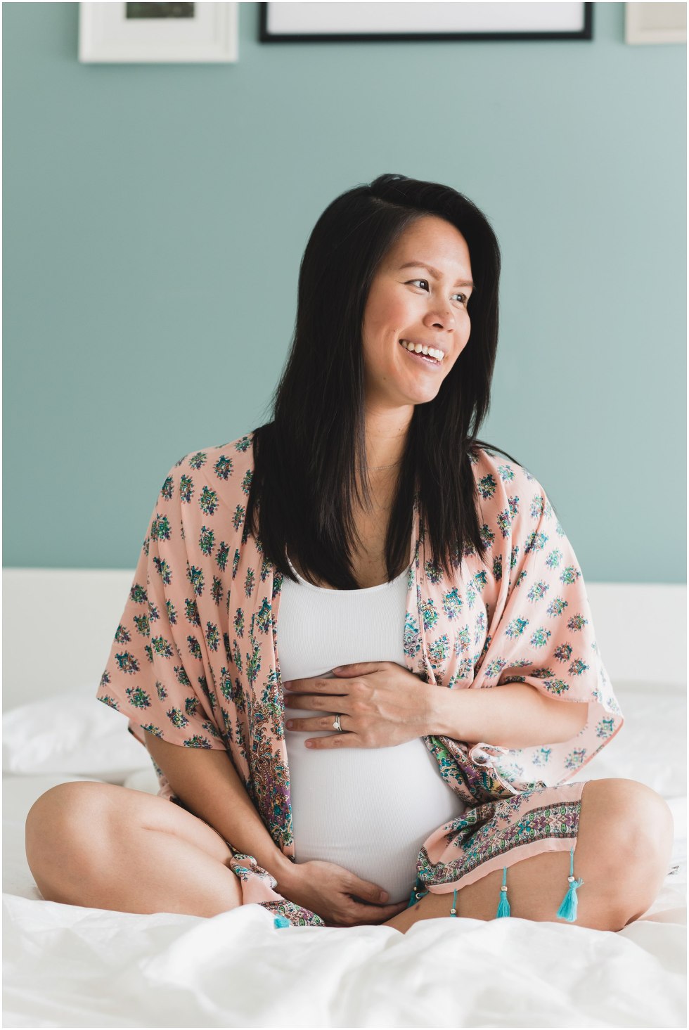 Pregnant woman holding her tummy and smiling, during her Toronto lifestyle maternity photos. 