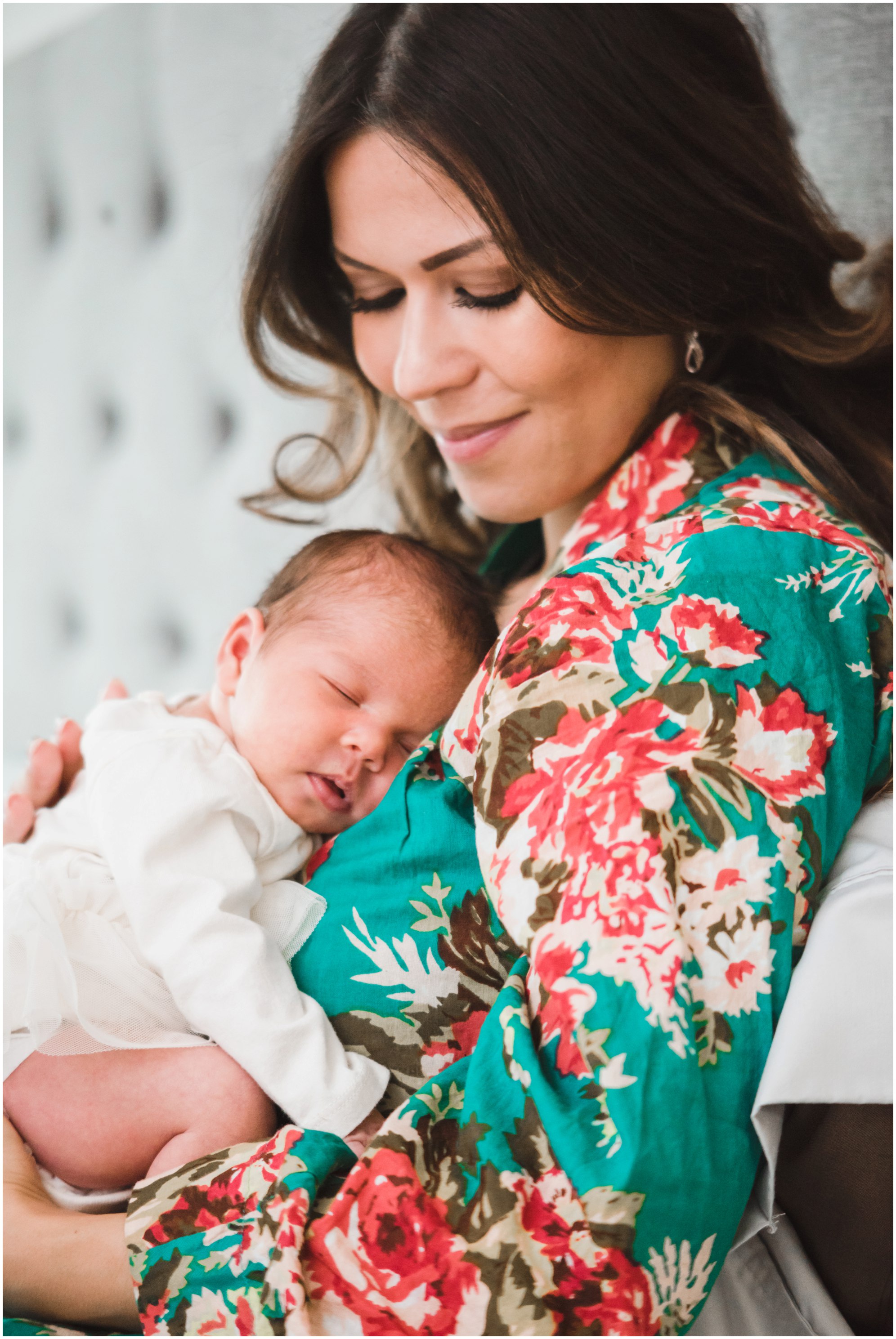 mother lying against headboard and smiling as baby sleeps against her chest Toronto family lifestyle photography