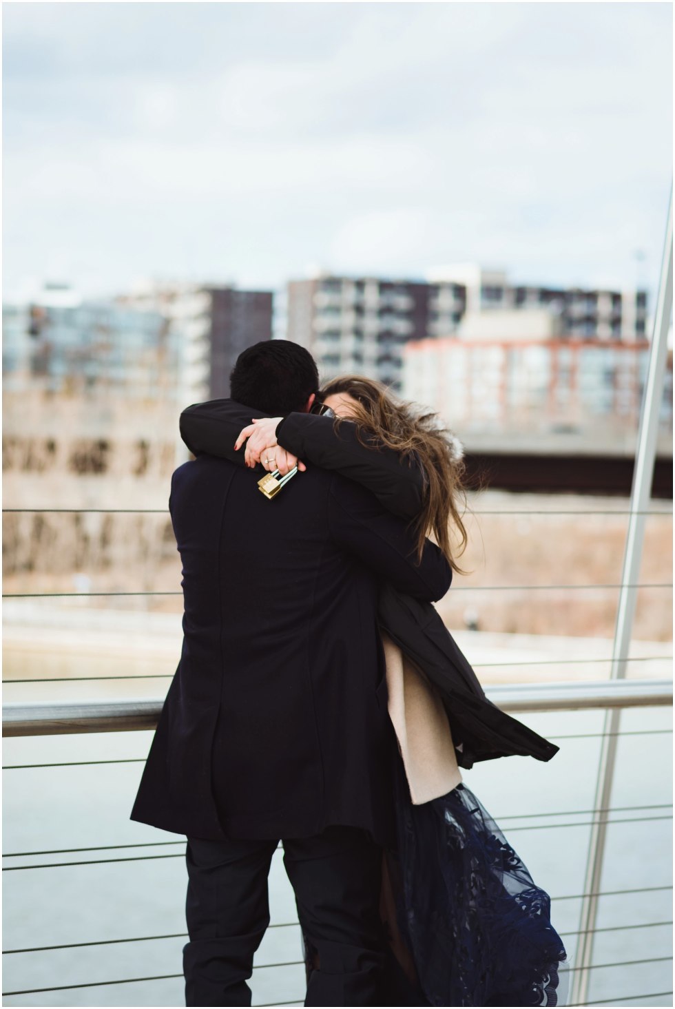 woman hugging man on bridge with locks in her hand Toronto proposal photography