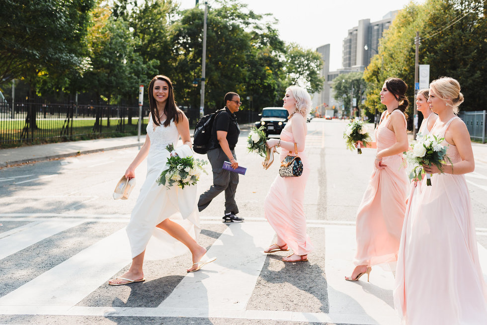 bride walking along street crossing with bridesmaids following behind her Toronto wedding photography 