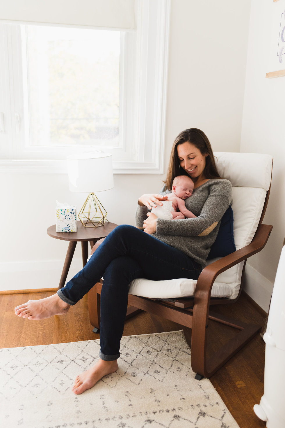 mom sitting in chair with newborn baby resting on her chest Toronto lifestyle photographer