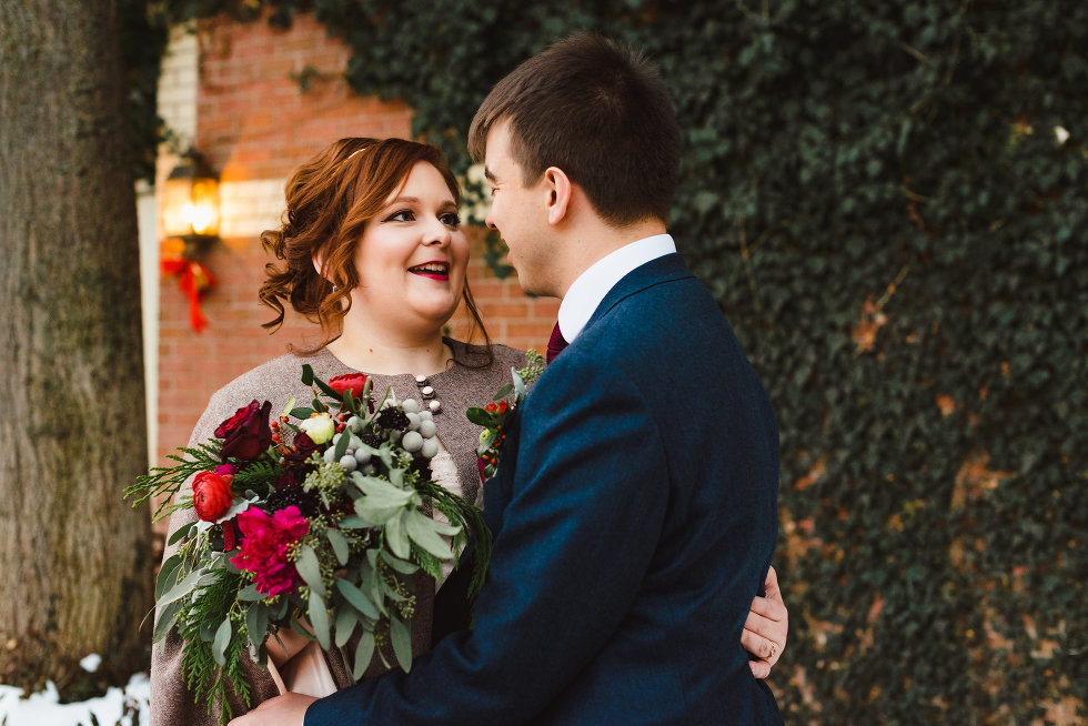 bride and groom in loving embrace with red bouquet between them Niagara wedding photography