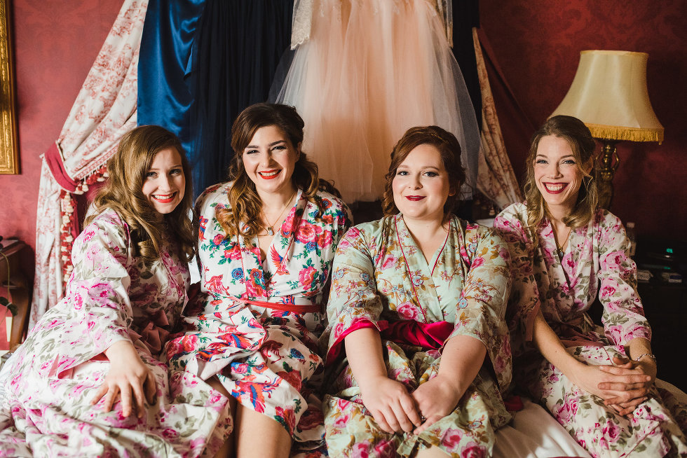 bride and her bridesmaids sitting on bed in floral robes Toronto wedding photography Gillian Foster