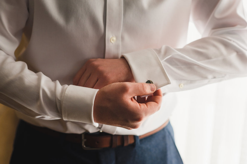 groom is attaching cufflinks to white shirt Toronto wedding photography