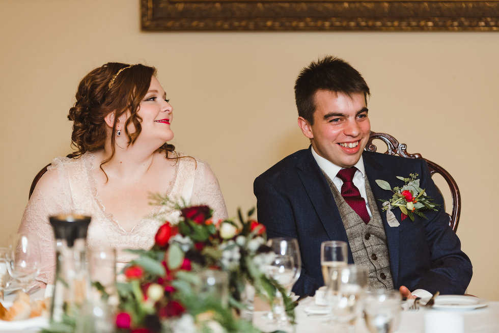 bride and groom smiling while sitting at head table Niagara wedding photography