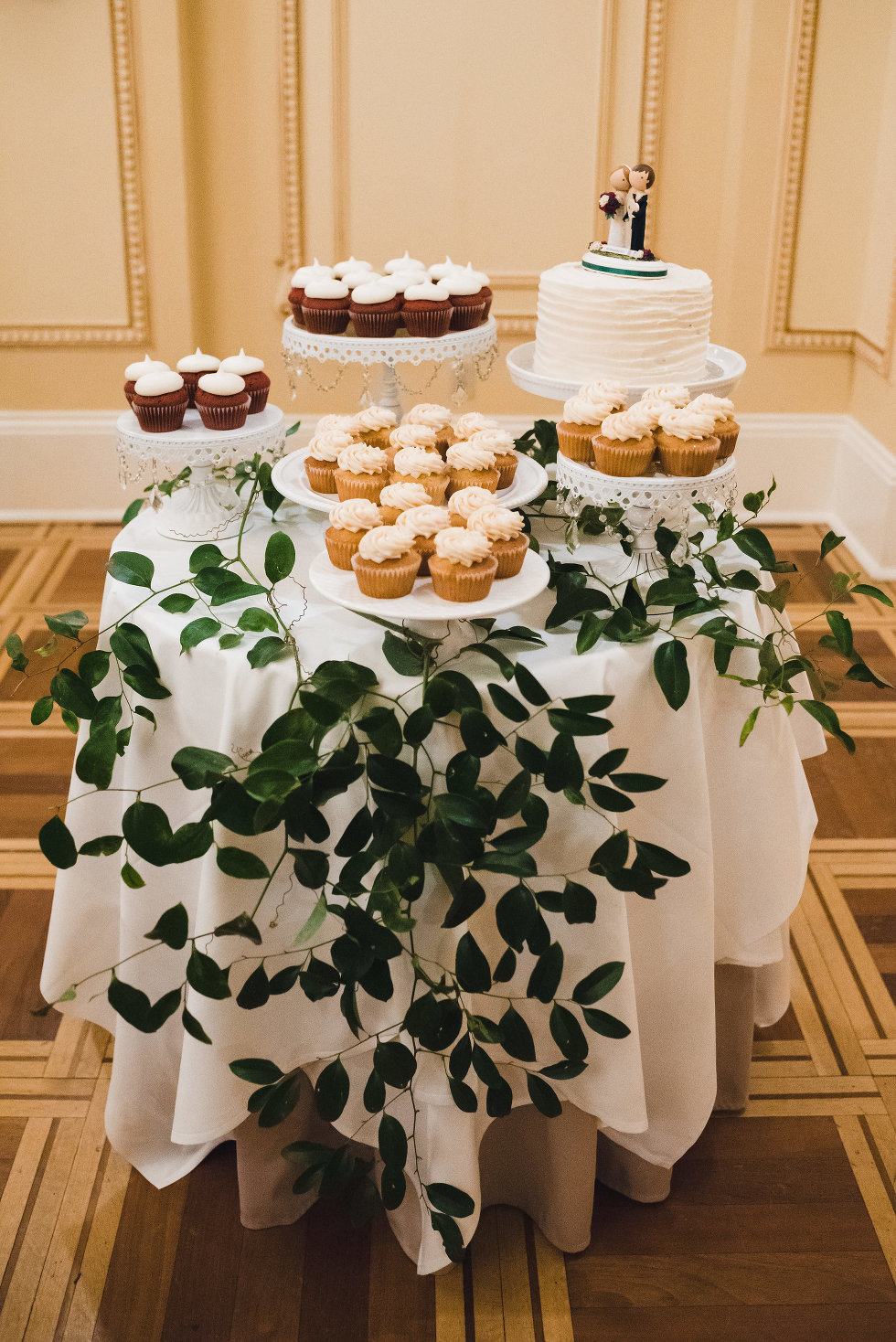 table with bride and groom topped wedding cake surrounded by cupcakes in Prince of Wales Hotel Niagara wedding photography