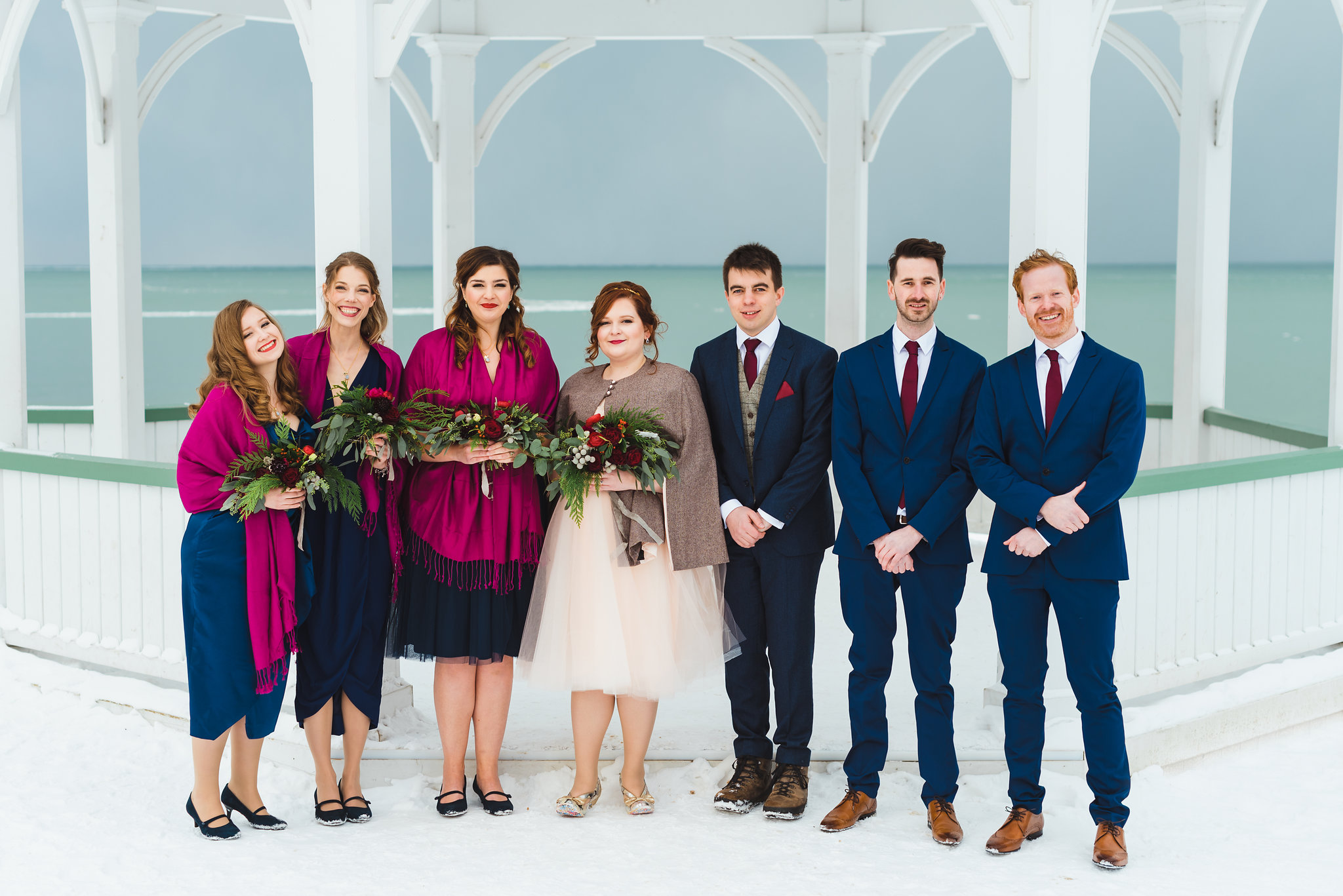 bride and groom stand with their wedding party in front of white gazebo Niagara wedding photography