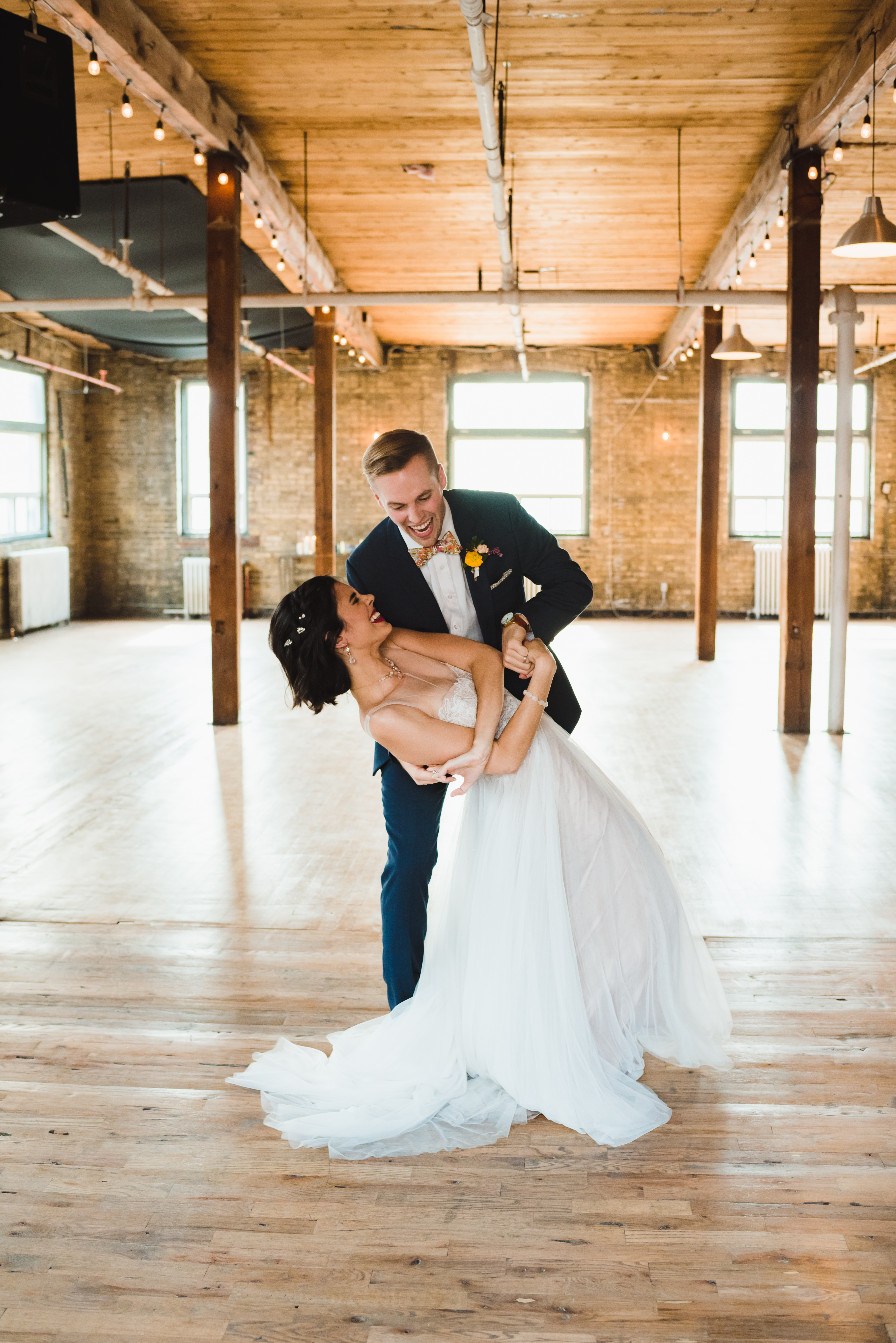 bride and groom laughing as groom dips his bride while dancing at the Jam Factory Toronto wedding photography