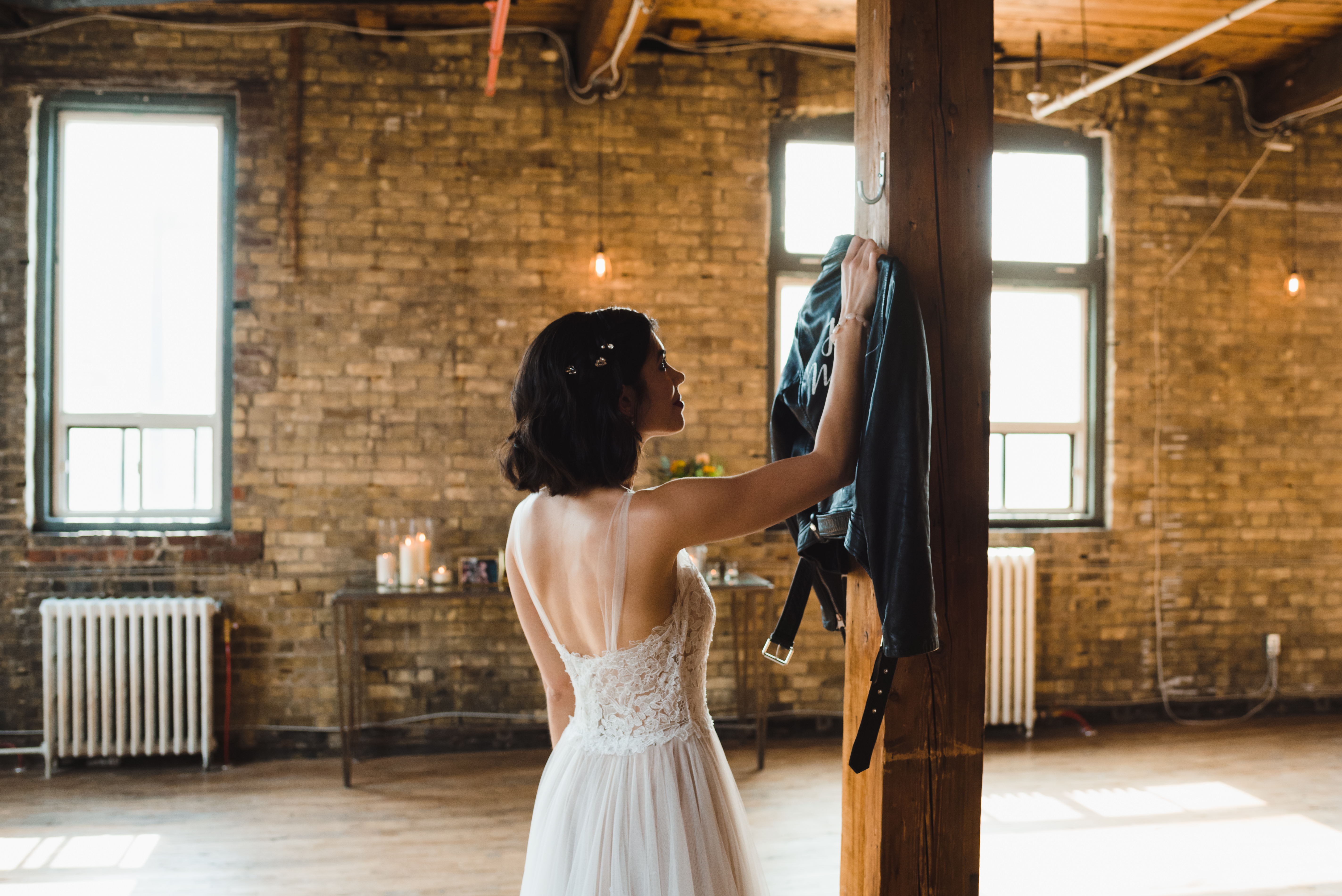bride reaching out to grab just married leather jacket off a hook Jam Factory Toronto wedding photography