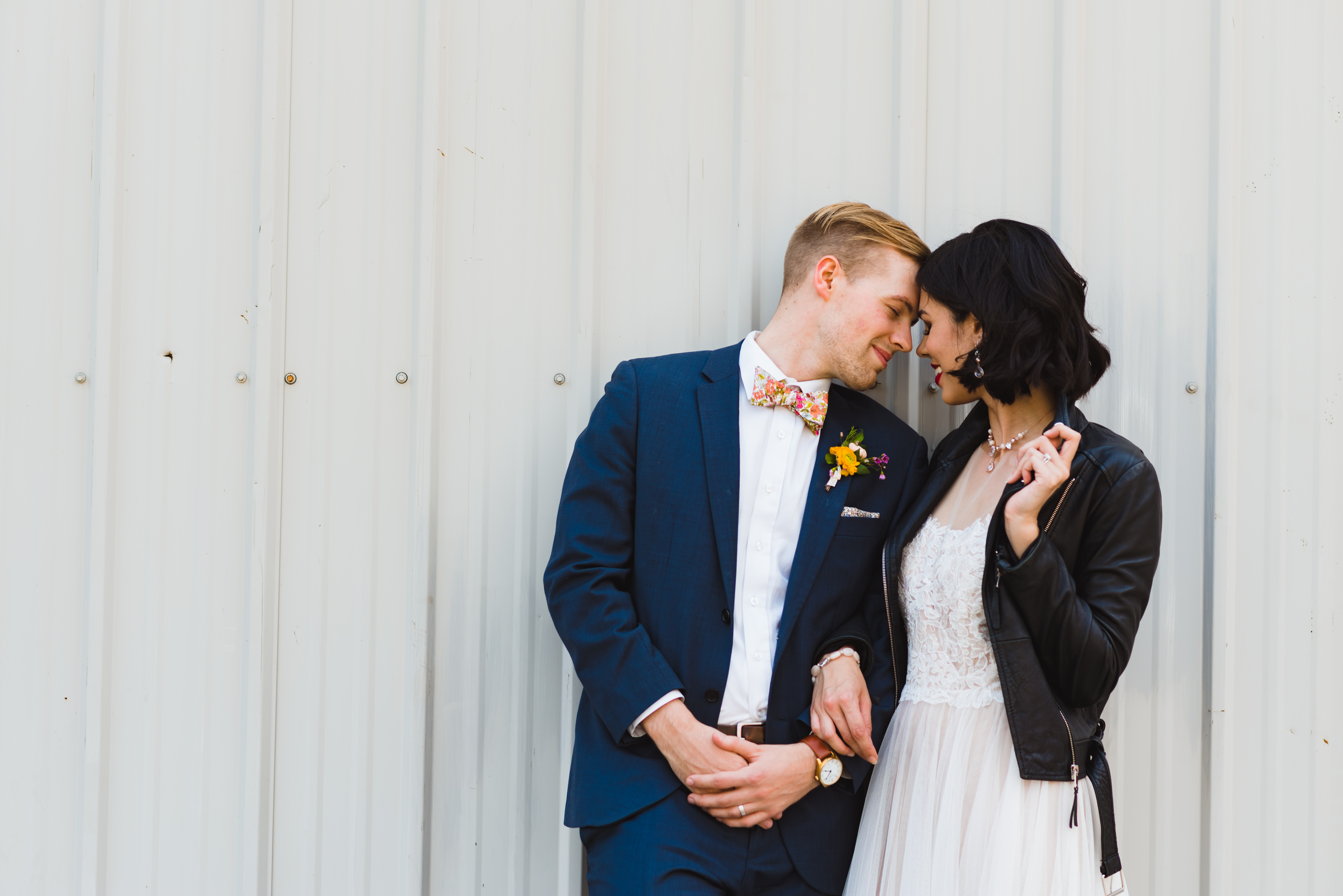 bride wearing just married leather jacket leaning against Jam Factory wall with groom