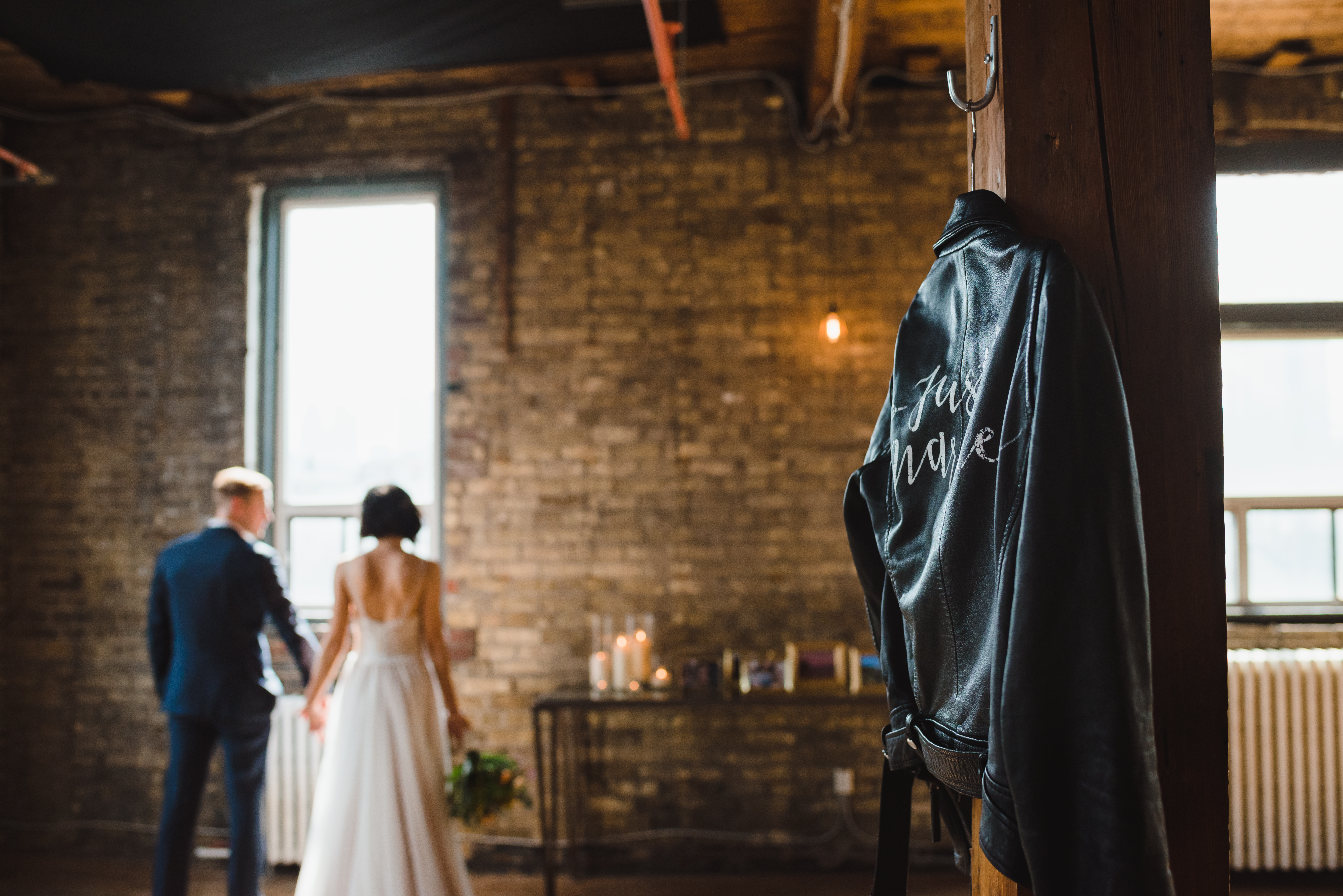 Just married leather jacket and bride and groom standing in font of window in background Jam Factory Toronto wedding photographer
