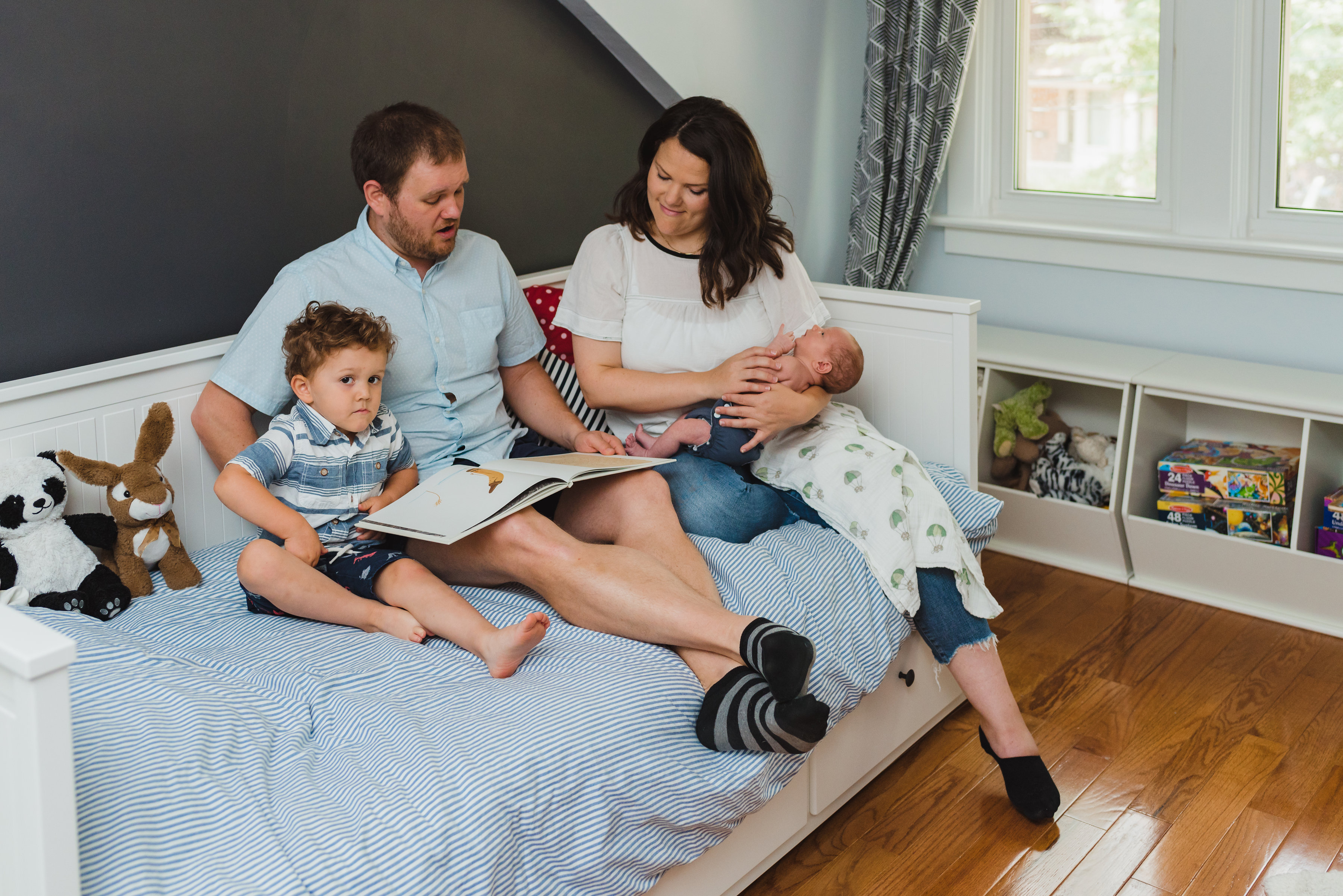 Documentary newborn photo session of parents reading to toddler and baby 