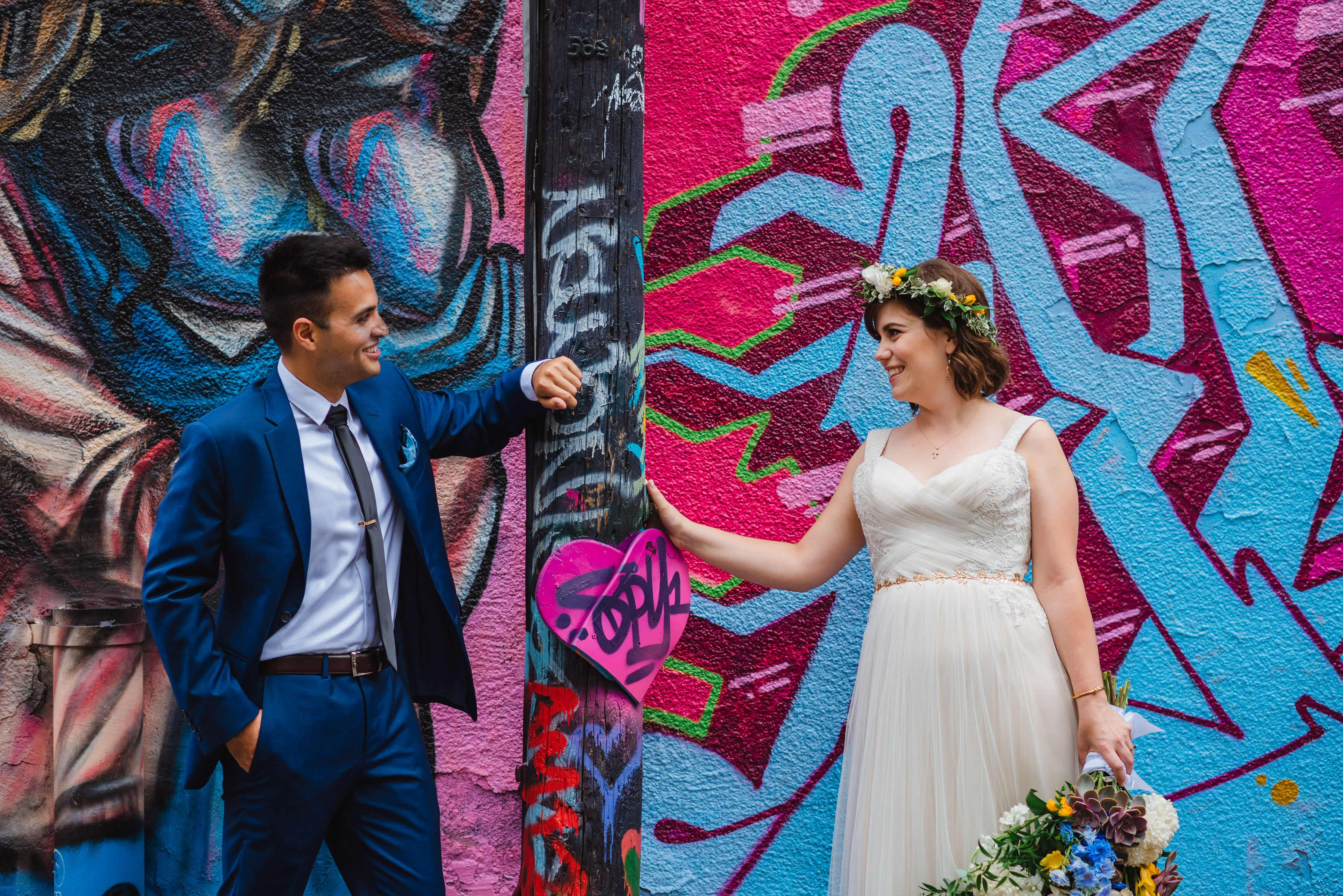 bride and groom leaning against a pole in Graffiti Alley in Toronto Junction Craft Brewing wedding photography