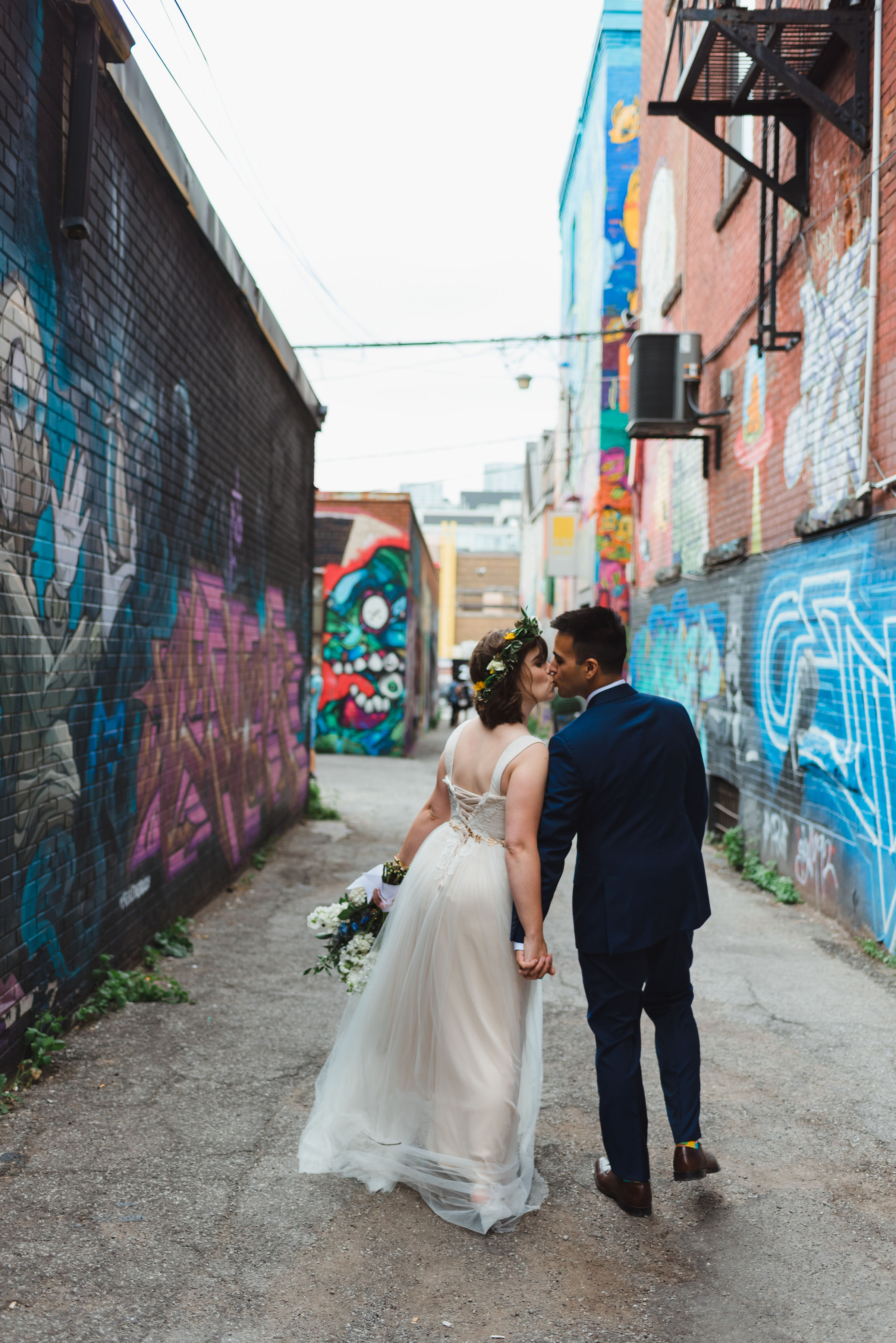 bride and groom strolling through Graffiti Alley in Toronto as they kiss Junction Craft Brewing