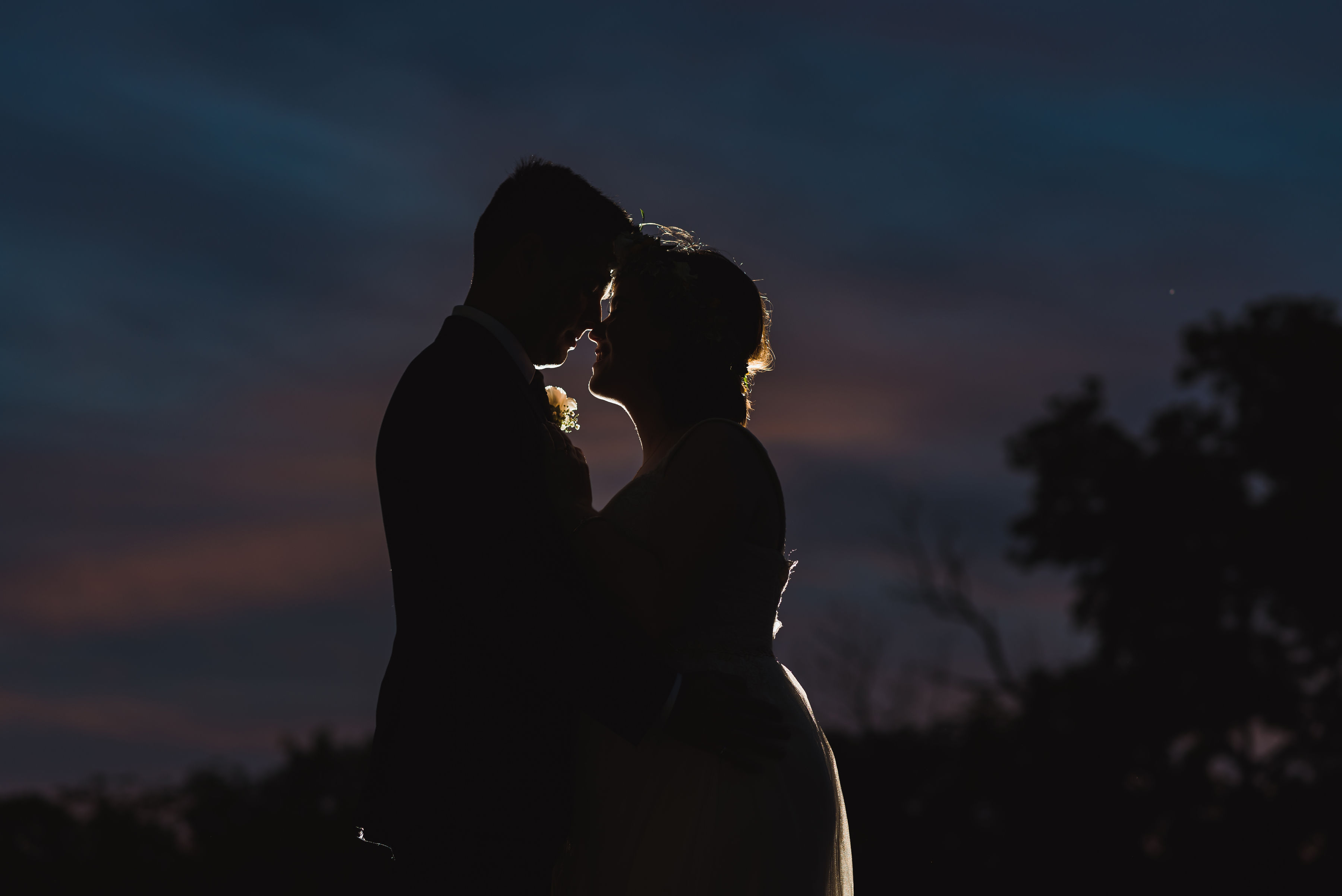 silhouette of a bride and groom holding each other at dusk Junction Craft Brewing Toronto wedding photographer Gillian Foster