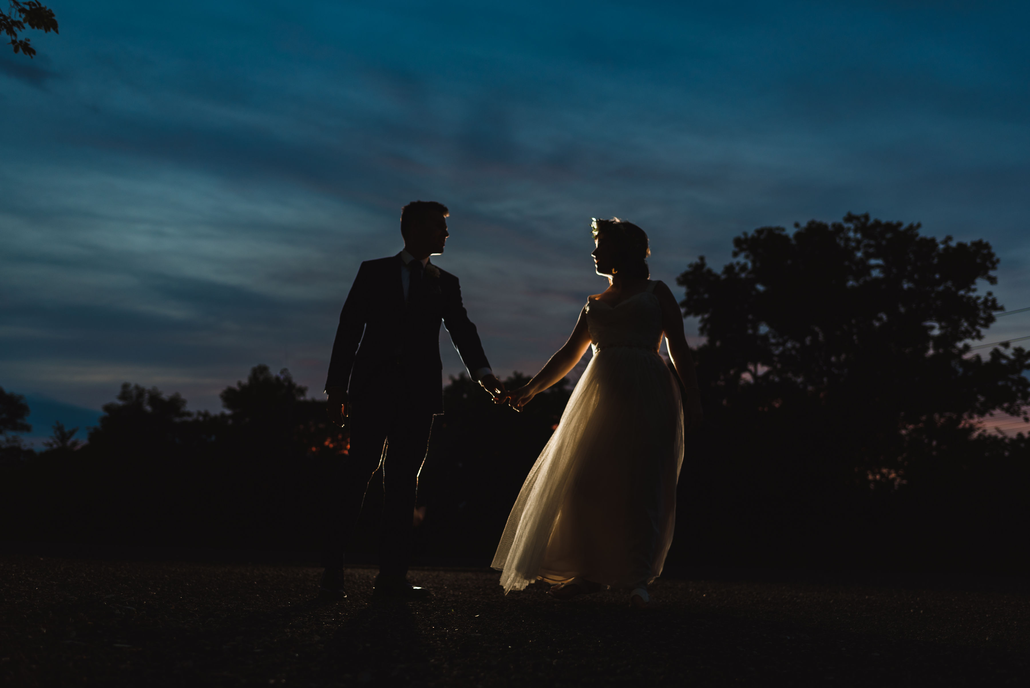 silhouette of a bride and groom holding hands at dusk Junction Craft Brewing Toronto wedding photographer Gillian Foster