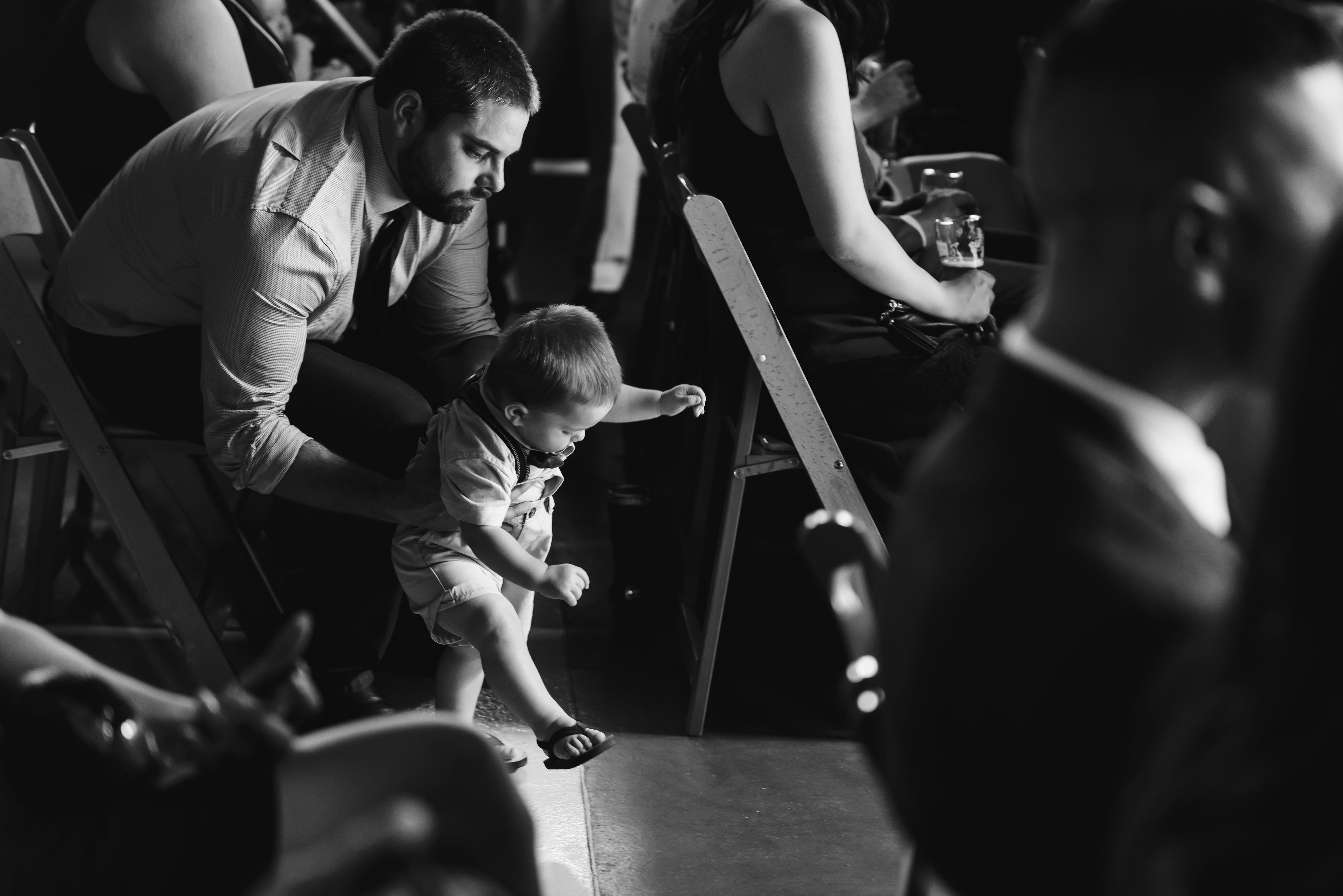 father holding his toddler up in the aisle before the wedding ceremony Toronto Junction Craft Brewing 