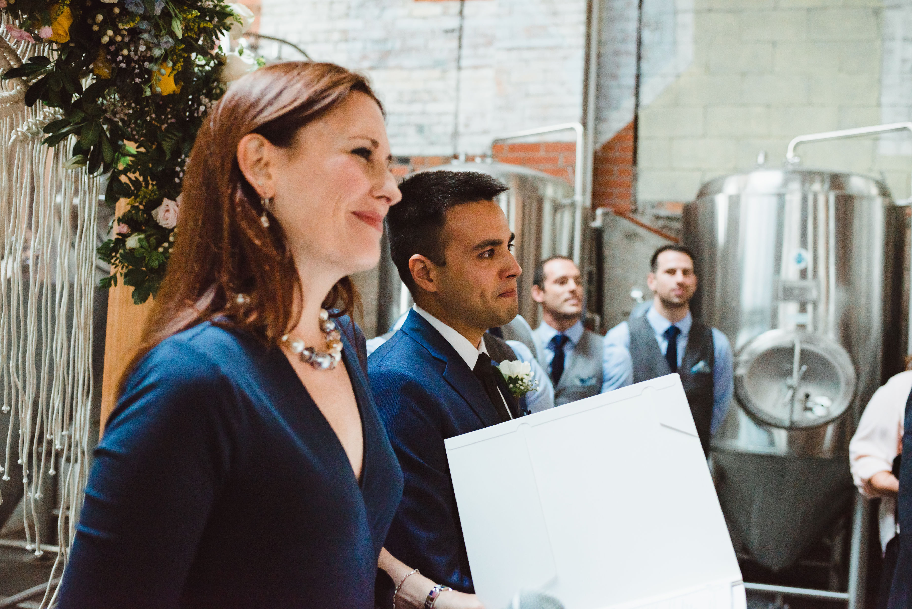 wedding officiant and groom smiling at the alter in front of brewing tanks Toronto Junction Craft Brewing wedding photography