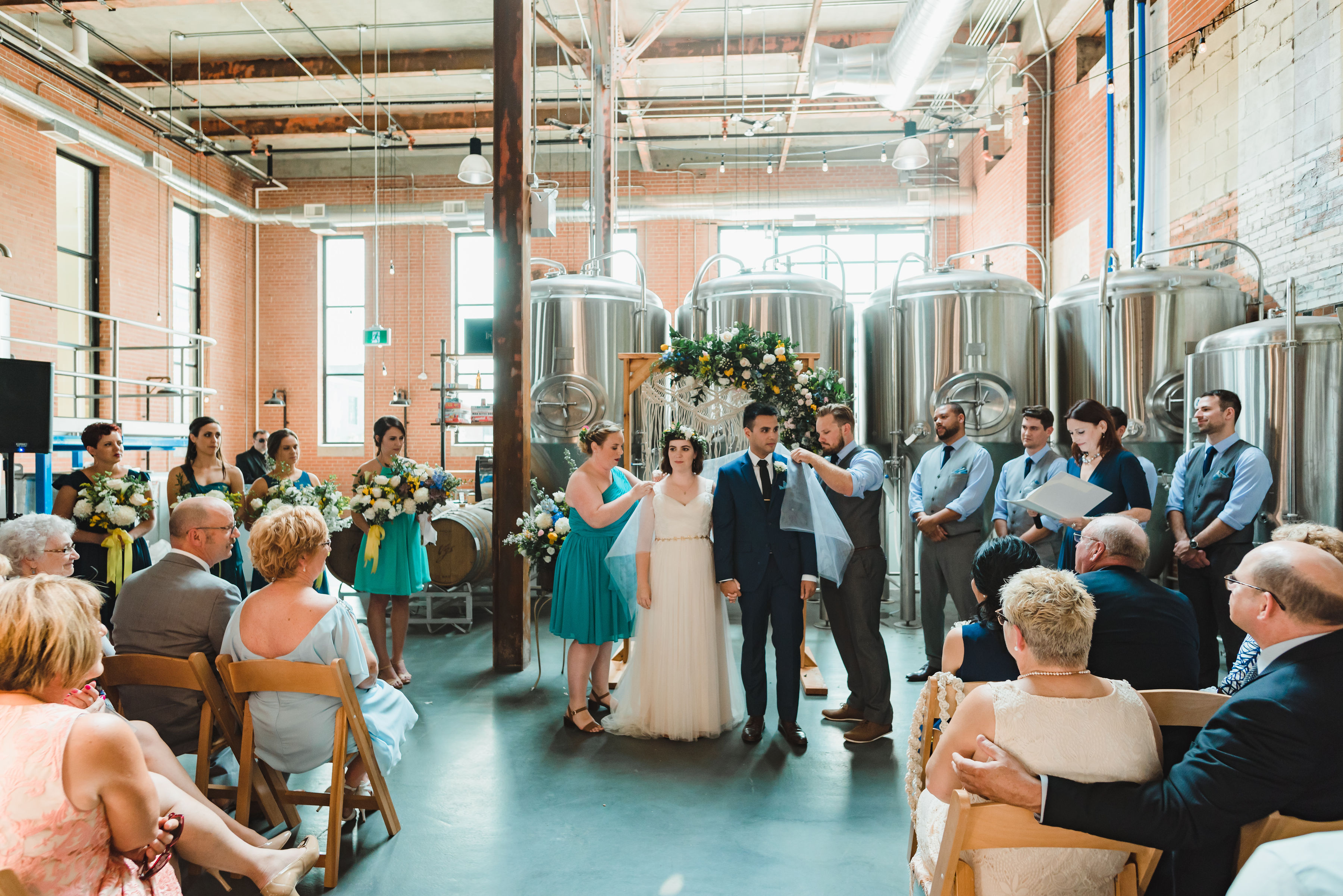 wedding ceremony in an old brewery with brewing tanks behind the alter Toronto Junction Craft Brewing