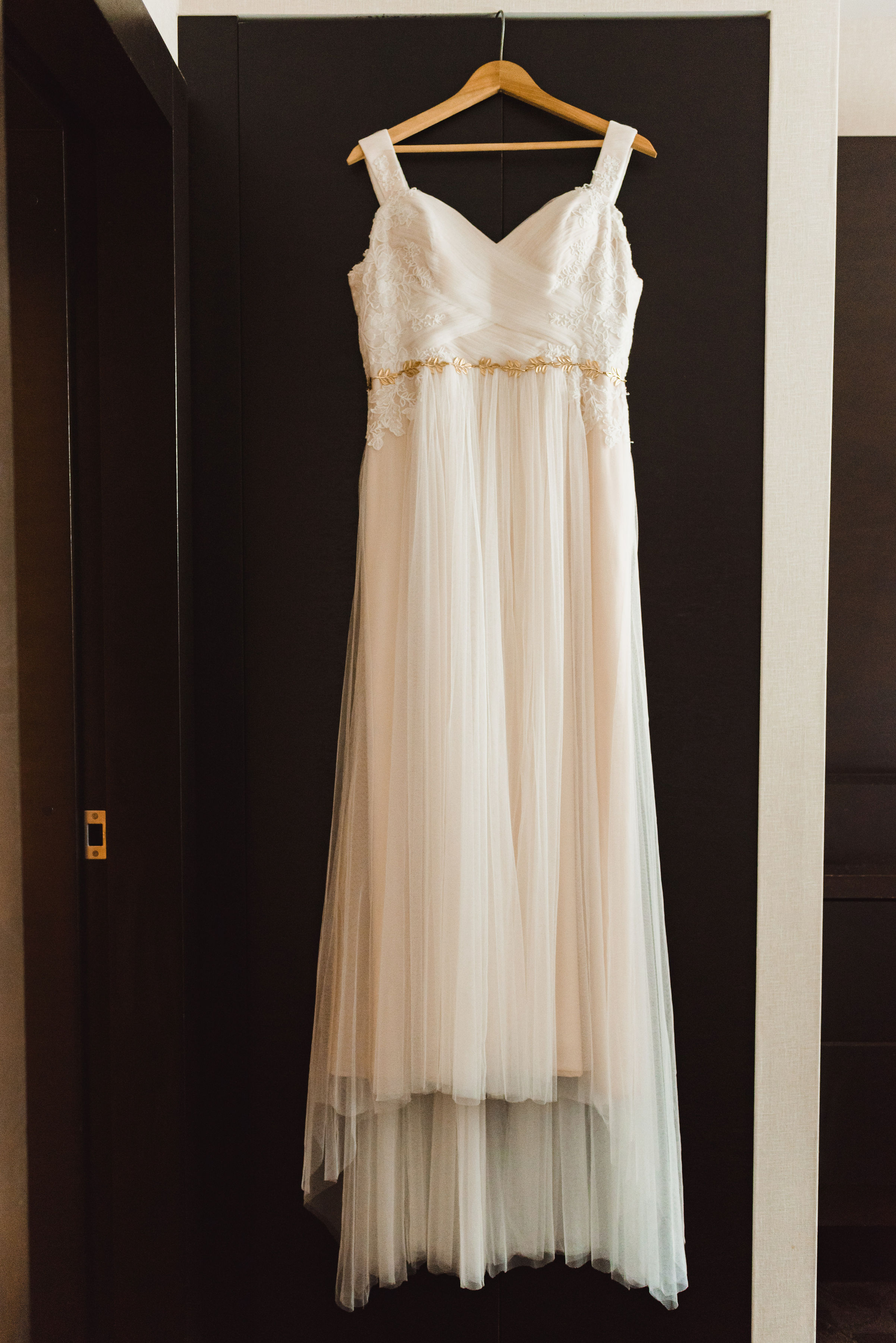 white wedding dress hanging on the back of a brown door Toronto brewery wedding photography 
