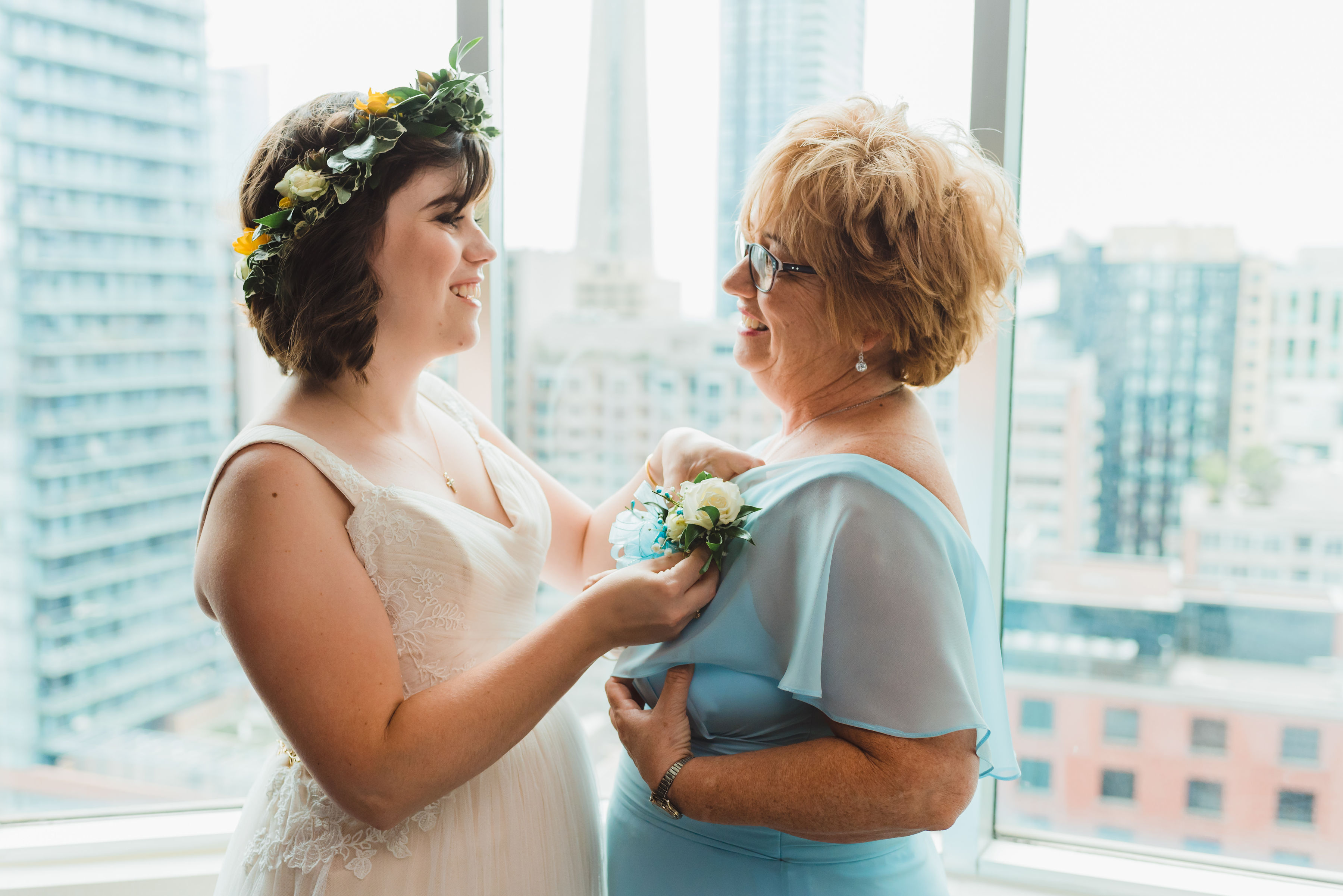 bride with flower crown placing boutonniere on her mothers blue dress Toronto brewery wedding photography