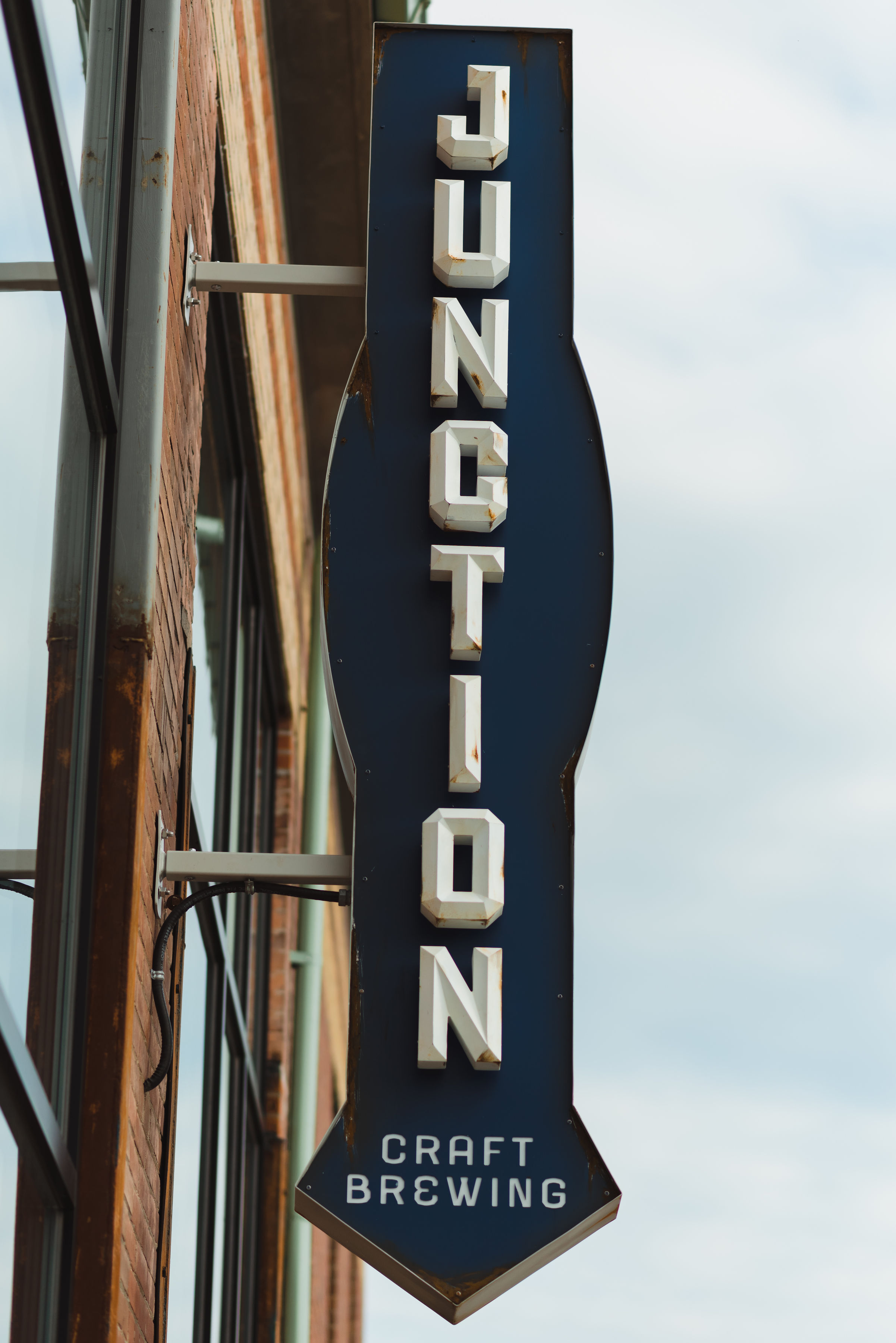 A blue and white brewery sign hanging off side of brick building that read Junction Toronto brewery wedding photography
