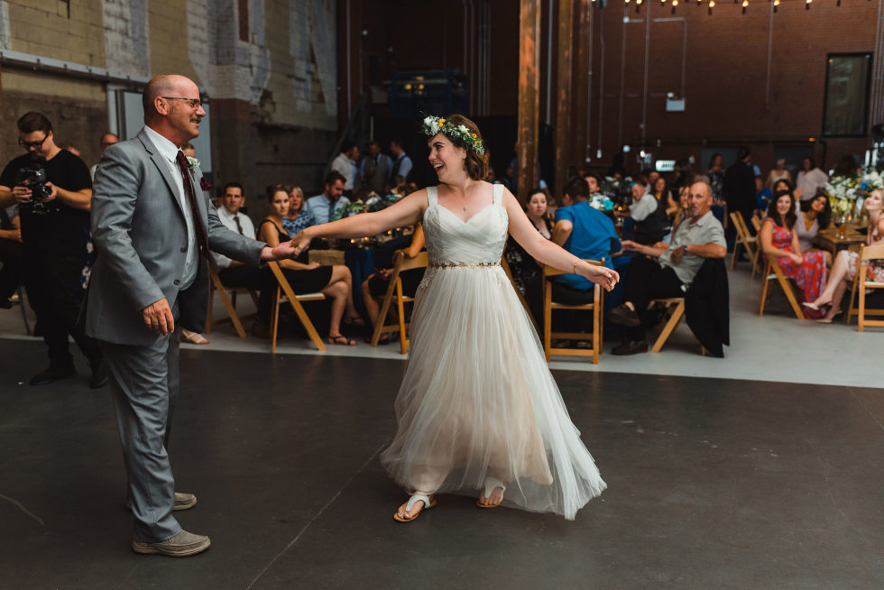 wedding guests watch from tables as bride and her father share a dance Junction Craft Brewing wedding photography