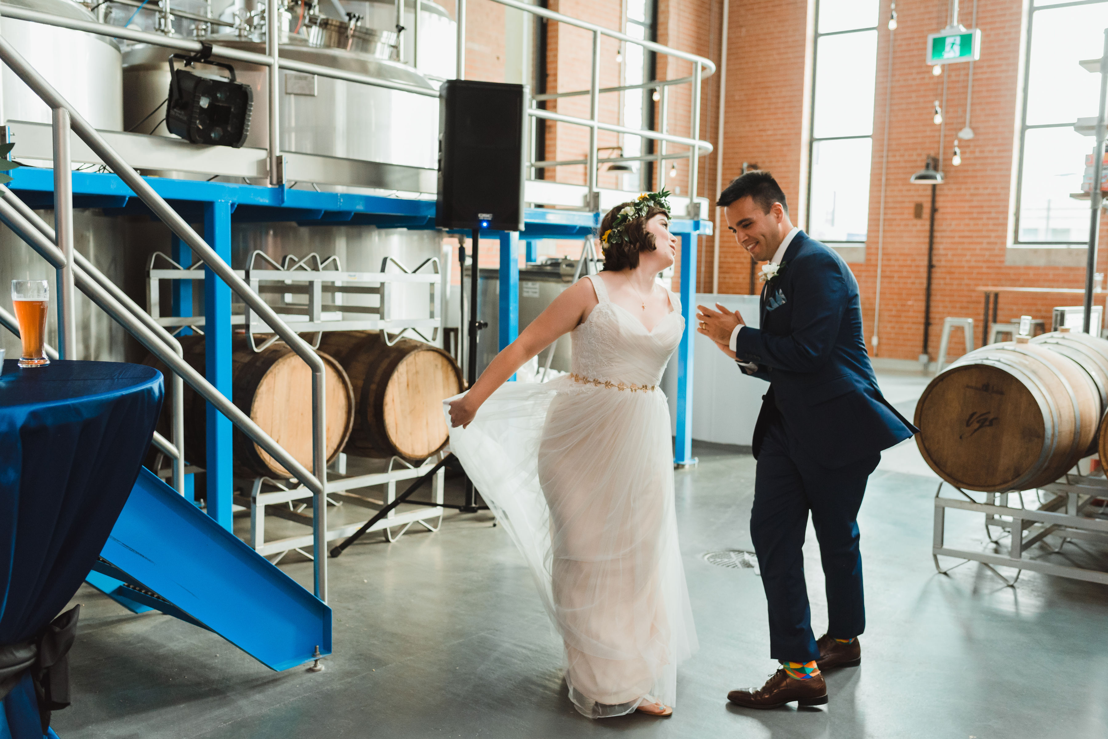 bride and groom dance as they enter wedding reception surrounded by beer barrels and brewing equipment Junction Craft Brewing wedding photography Toronto
