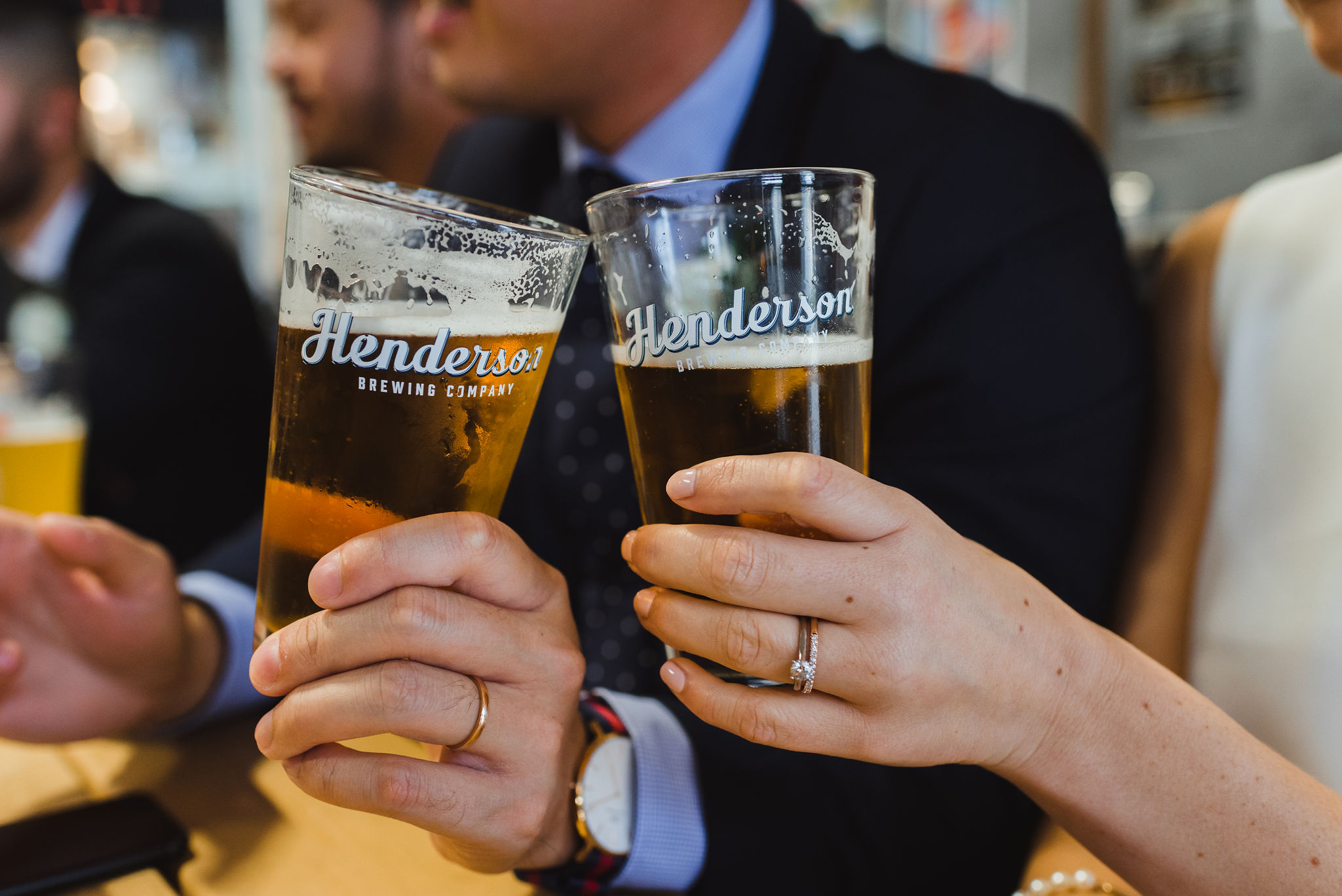 bride and groom toasting each other with pints of beer at Henderson's Brewing Company Toronto