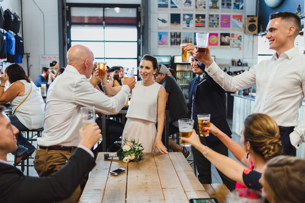 bride and groom toasting the wedding guests at a picnic bench in Henderson Brewing Company Toronto wedding