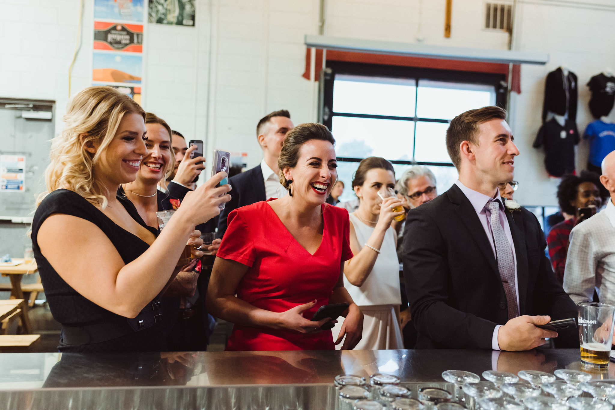 wedding guests and bride laughing and drinking pints at the bar in Henderson's Brewing Company Toronto 