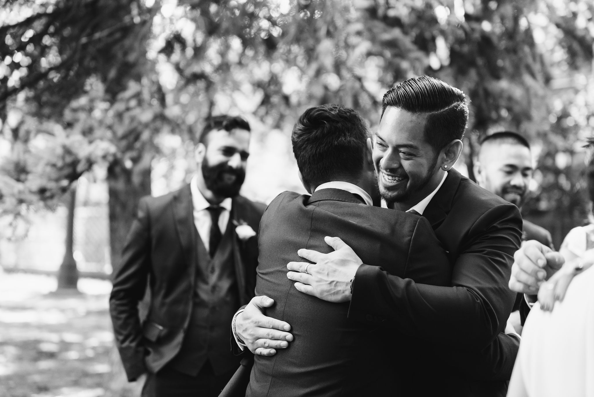 groomsman hugging groom during wedding ceremony in Trinity Bellwoods Park Toronto