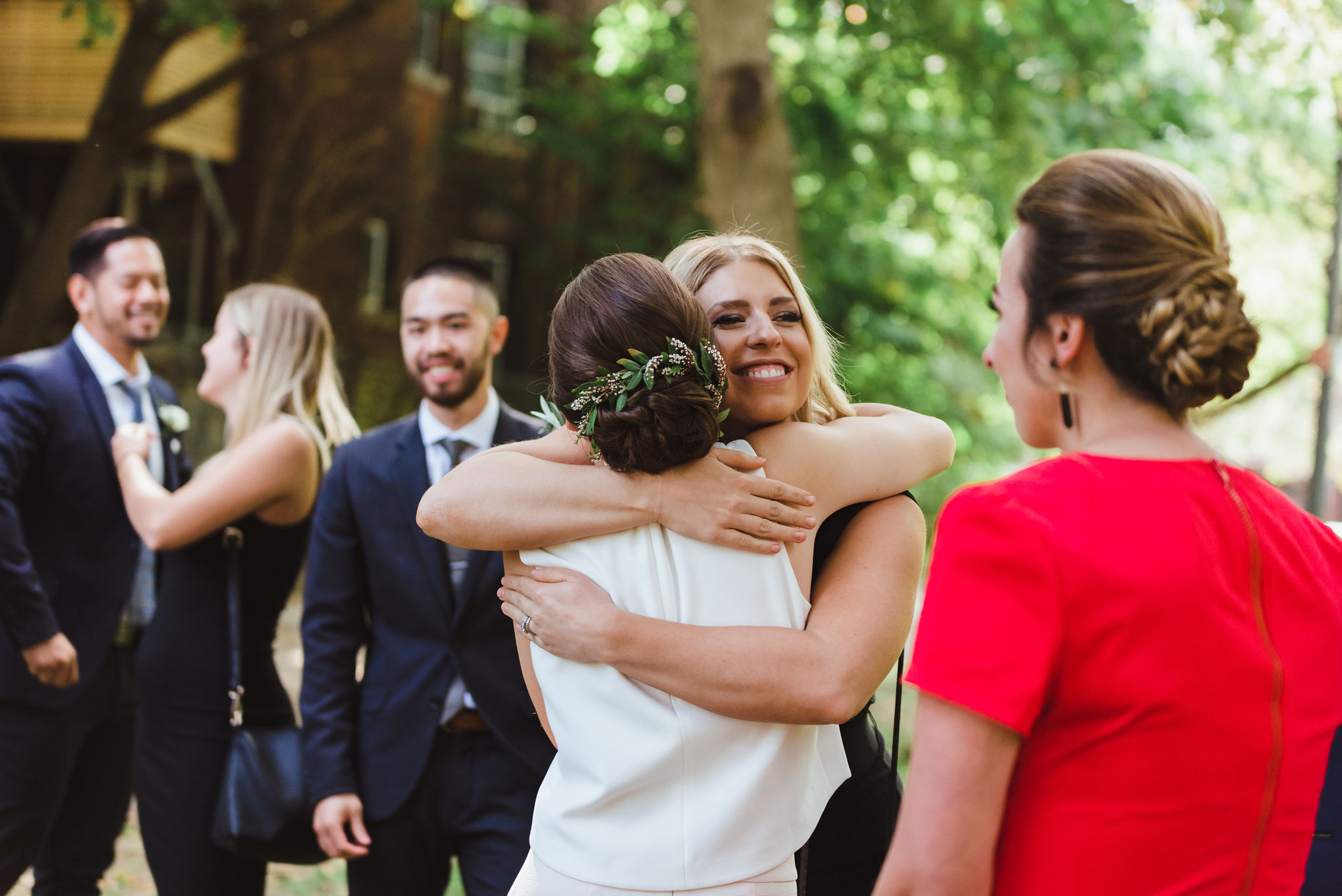 bride hugging bridesmaid during wedding ceremony in Trinity Bellwoods Park Toronto