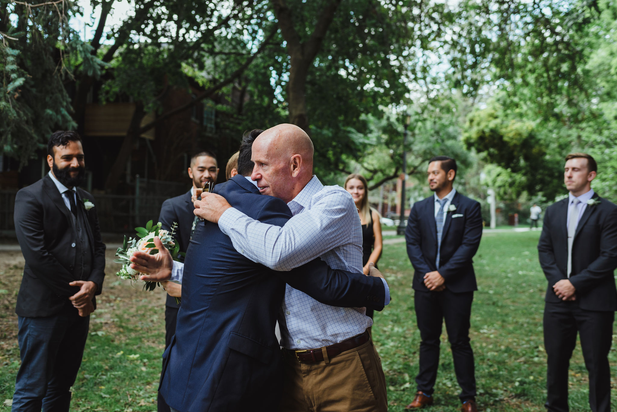 bride's father hugging groom before ceremony in Trinity Bellwoods Park Toronto Canada