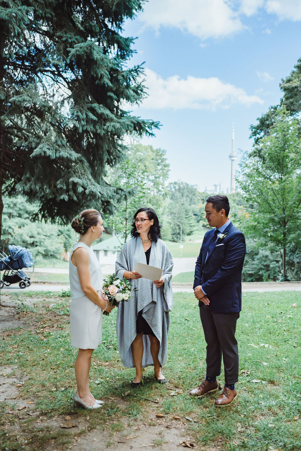 bride and groom stand before officiant during wedding ceremony Trinity Bellwoods wedding Toronto