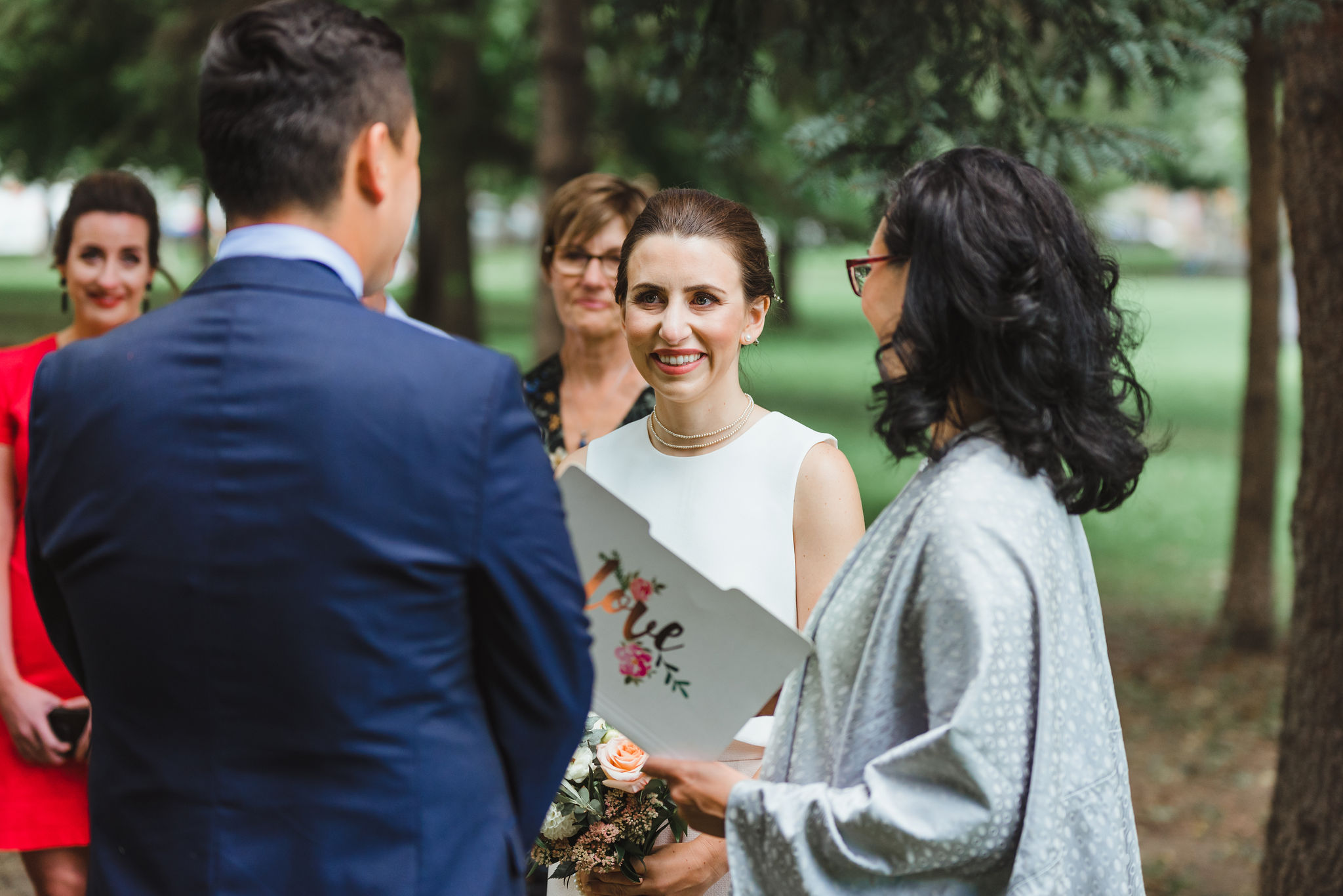 bride smiling at groom during wedding ceremony in Trinity Bellwoods Park Toronto Canada