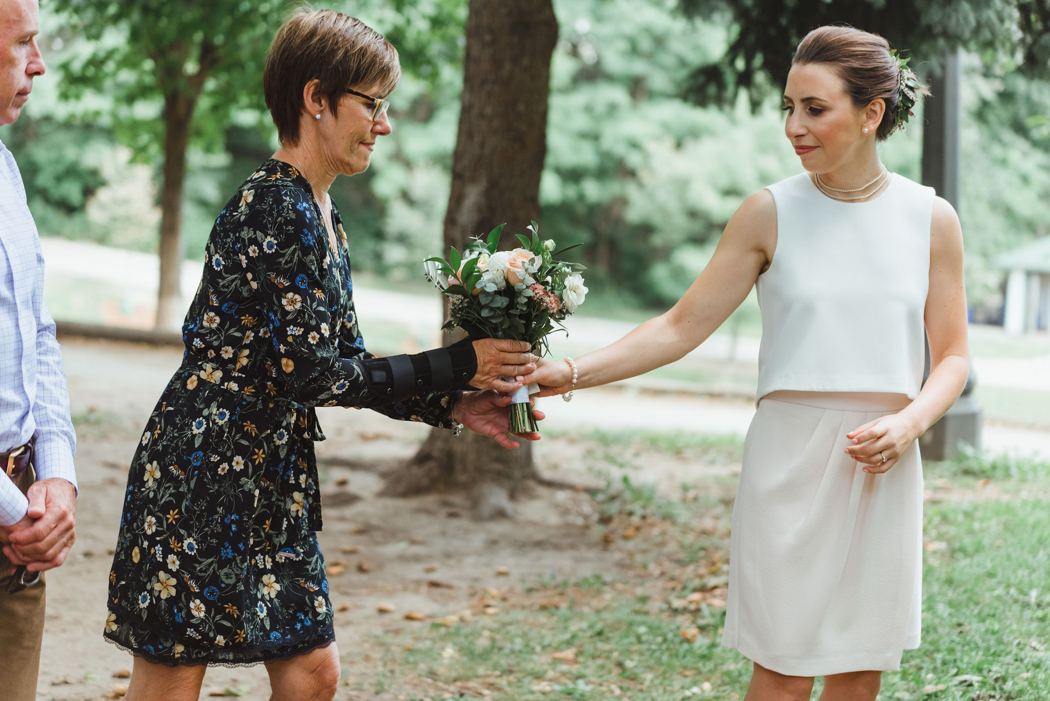 bride handing her mother her bouquet of flowers during wedding ceremony in Trinity Bellwoods Park Toronto