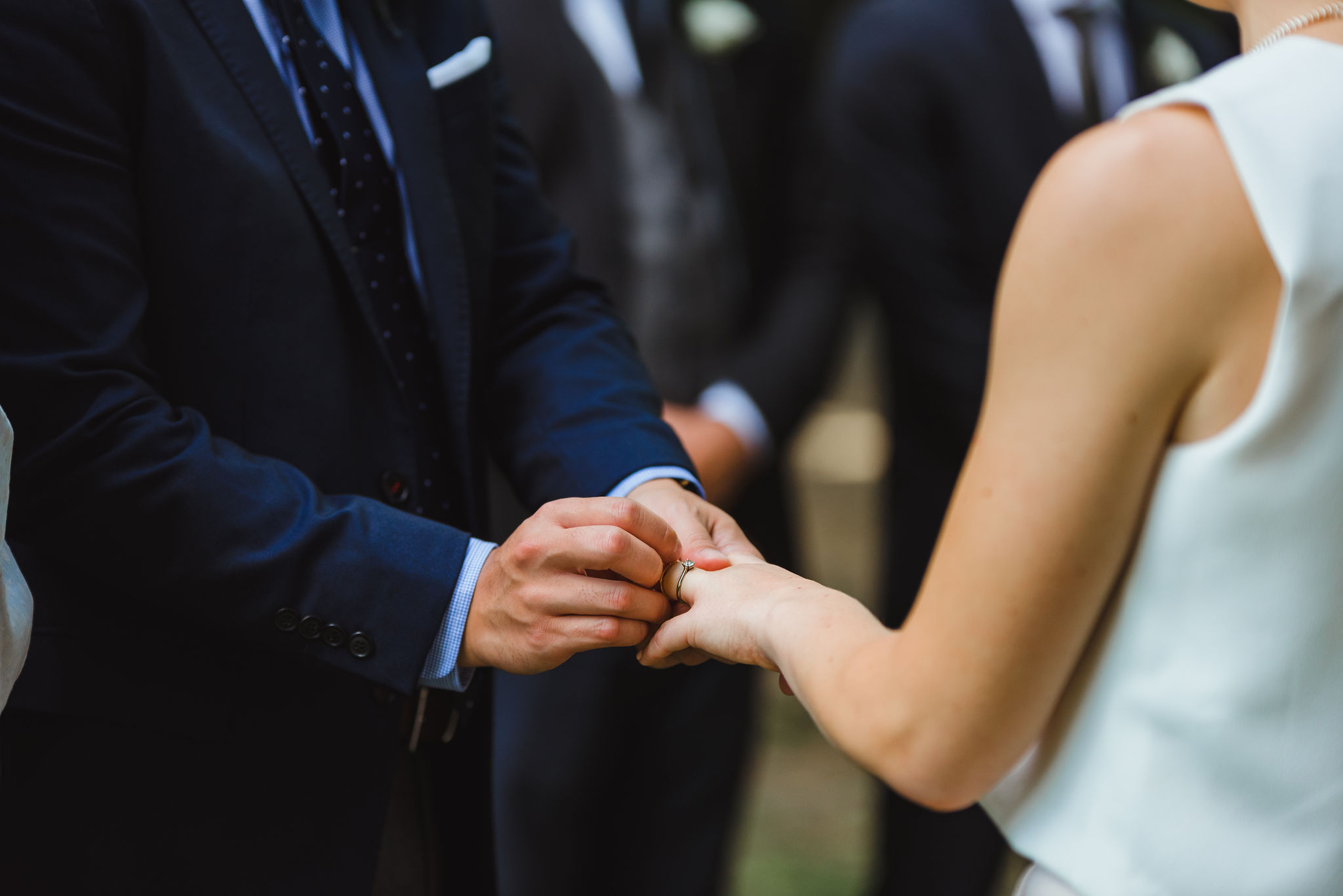 groom placing ring on bride's finger during ceremony in Trinity Bellwoods Park Toronto