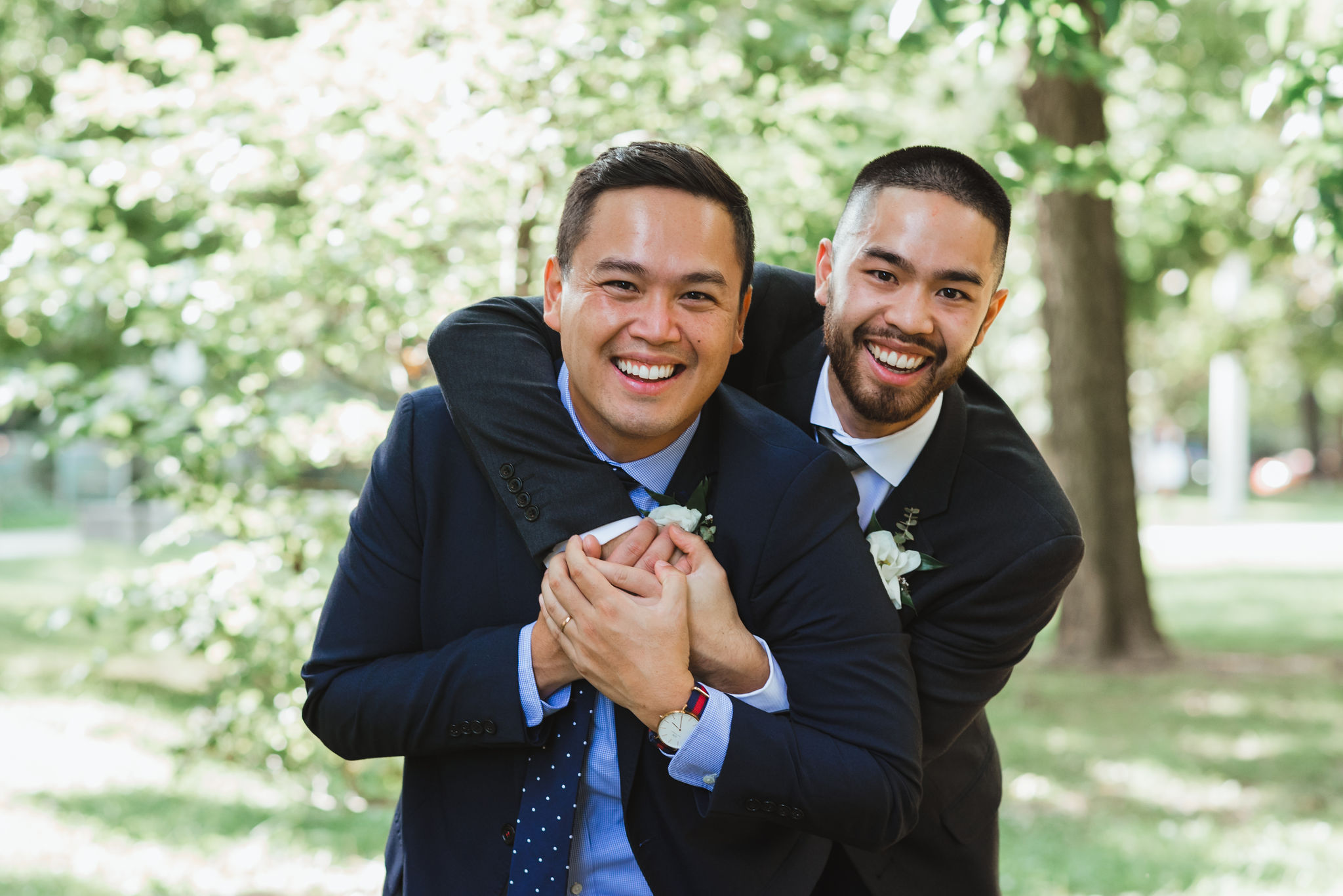 groomsman with his arms swung around the groom as they smile Trinity Bellwoods Park wedding ceremony Toronto