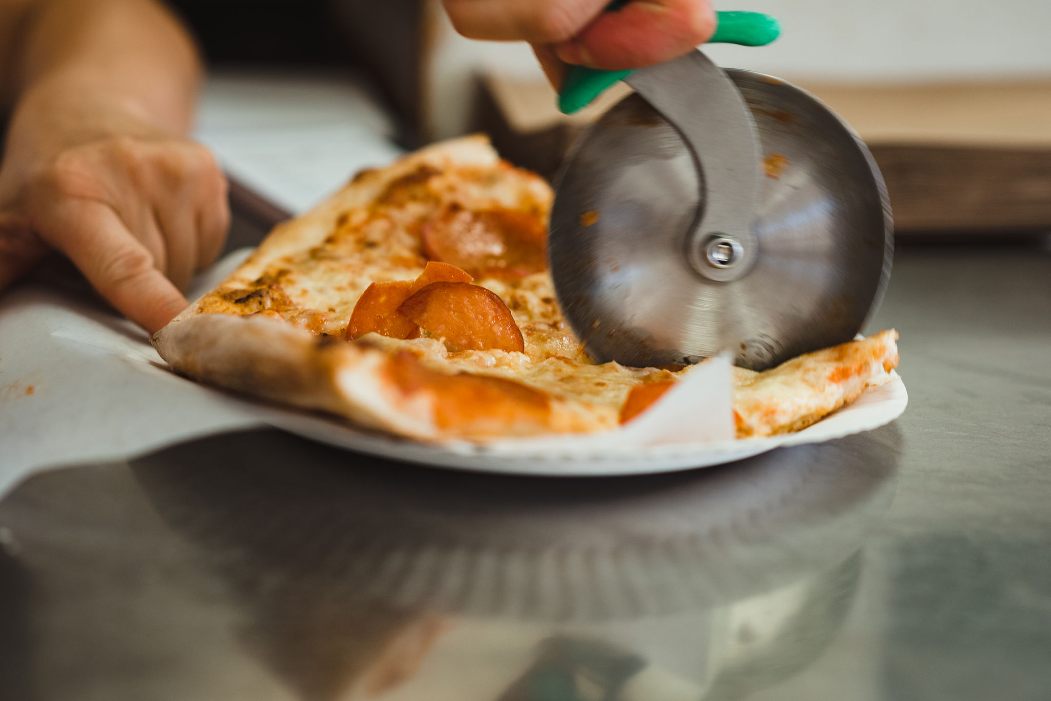 pizza cutter cutting through a slice of pepperoni pizza at Bitondo's Pizzeria Toronto Canada